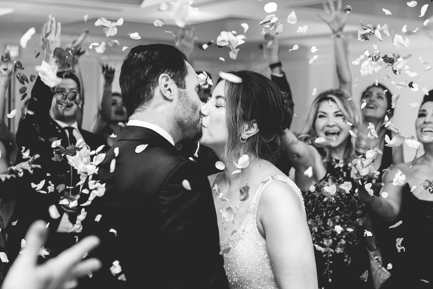 Wedding celebration with people dancing and confetti falling during a joyful reception party.