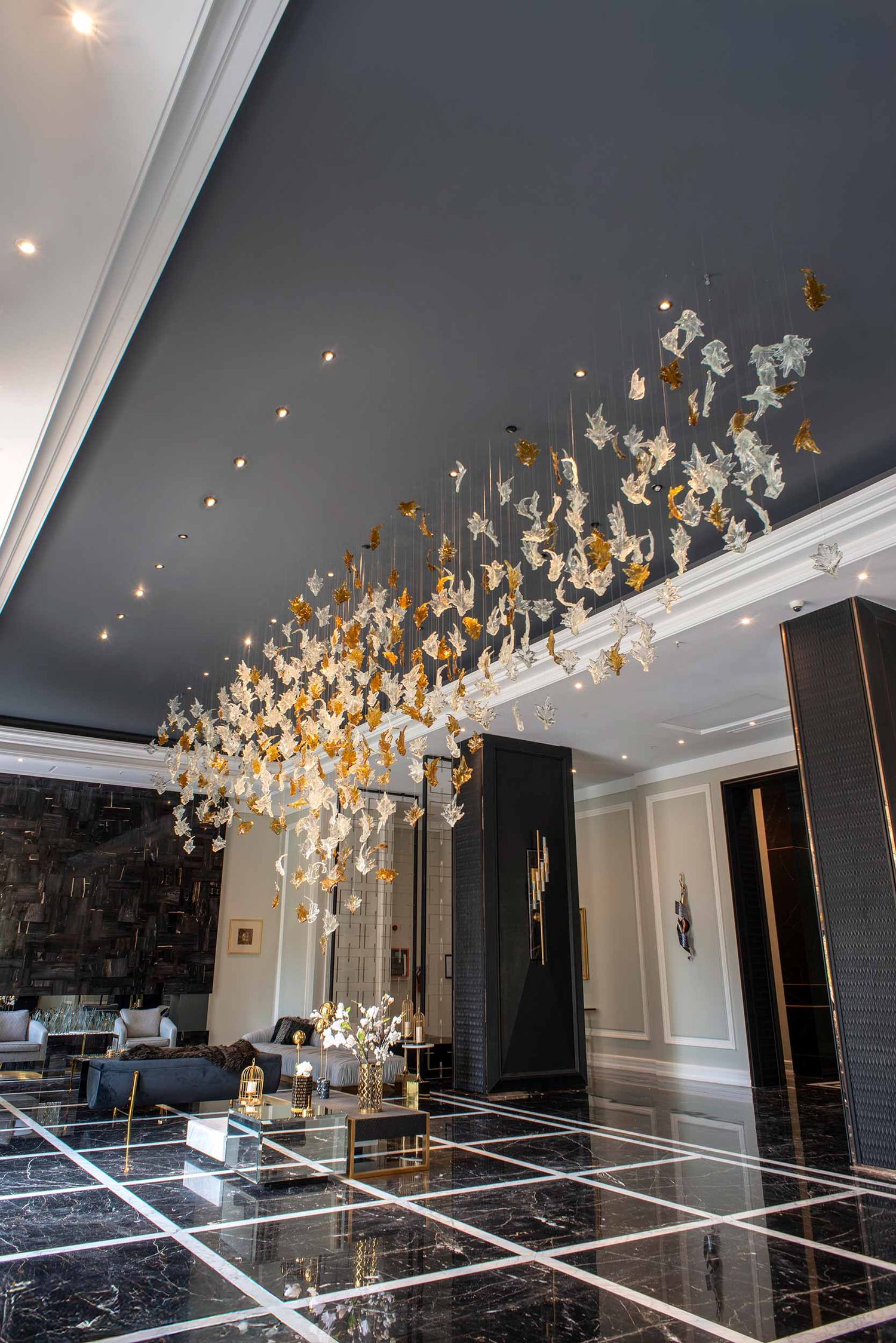 Luxurious hallway features glossy black floors and a stunning art installation of white and gold butterflies floating across the ceiling.
