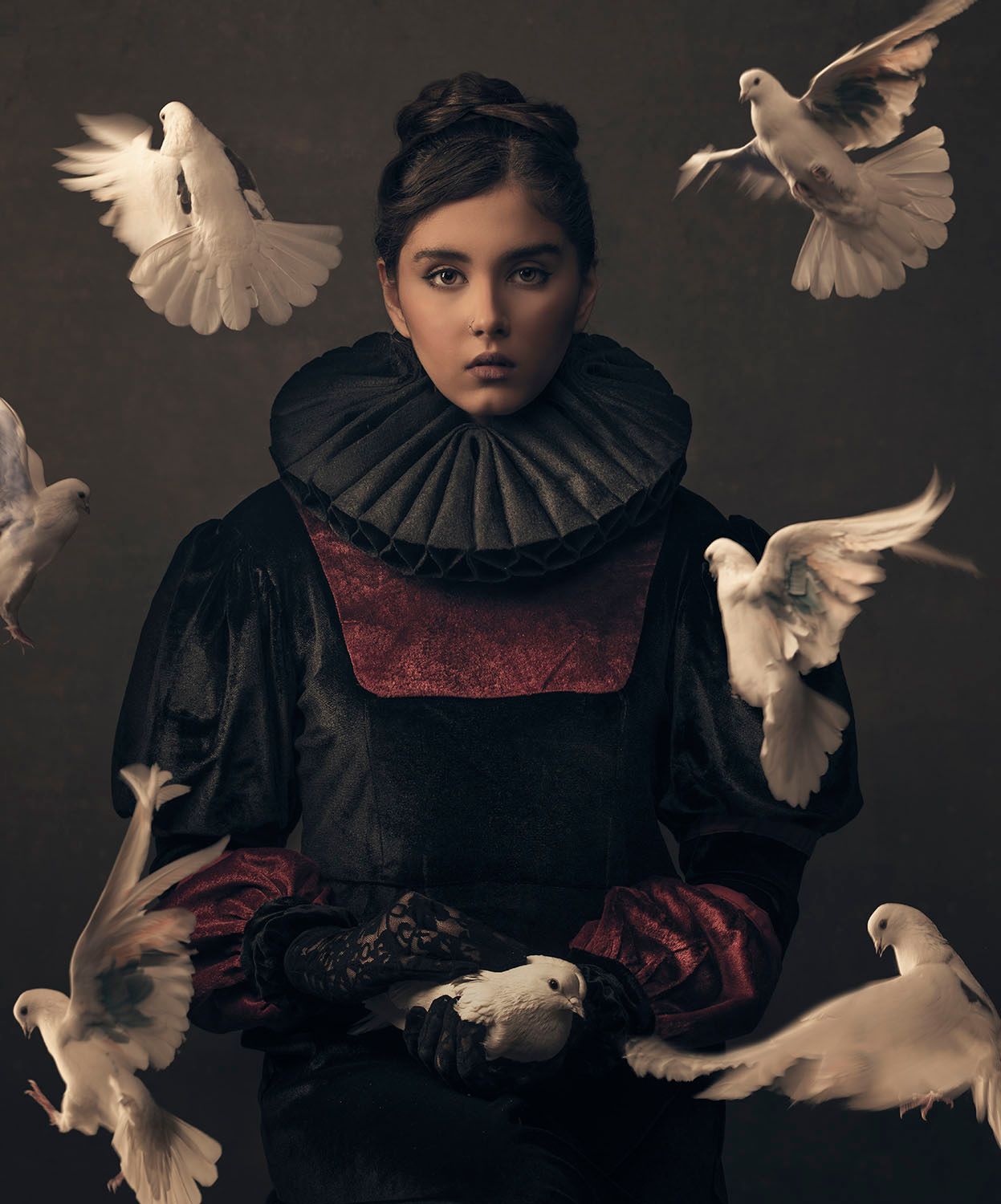 Young girl in Renaissance costume surrounded by white doves in dramatic dark artistic portrait.