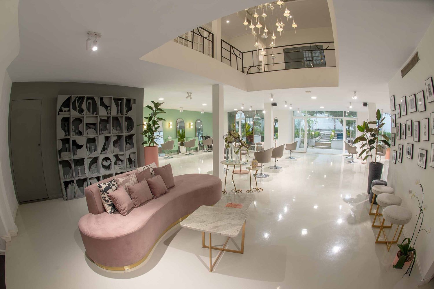 Modern white interior design with curved pink sofa, geometric shelving and open floor plan with marble floors and potted plants.