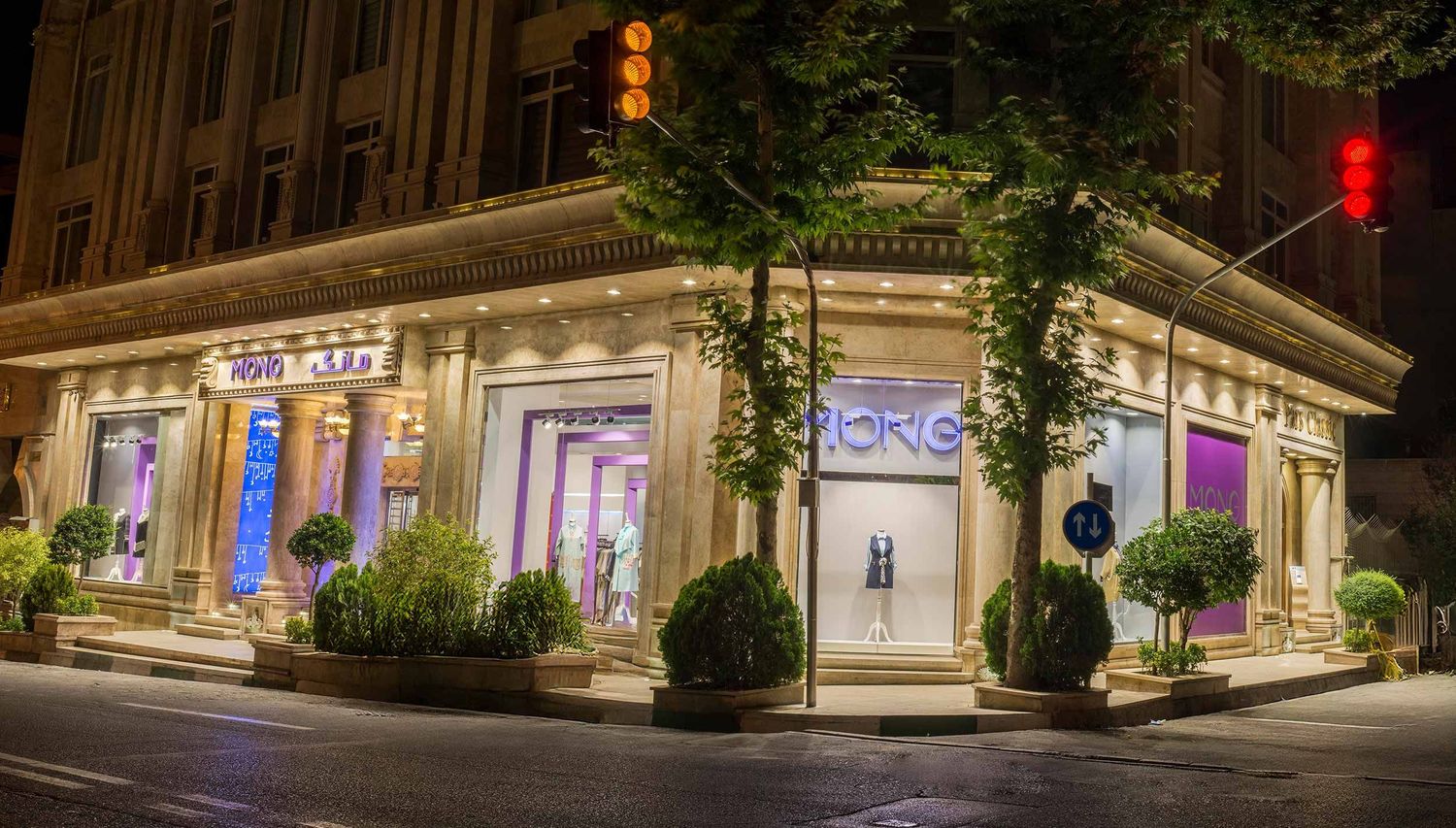 Illuminated corner storefront with Michael Kors signage features elegant window displays and ornate architectural details at night.