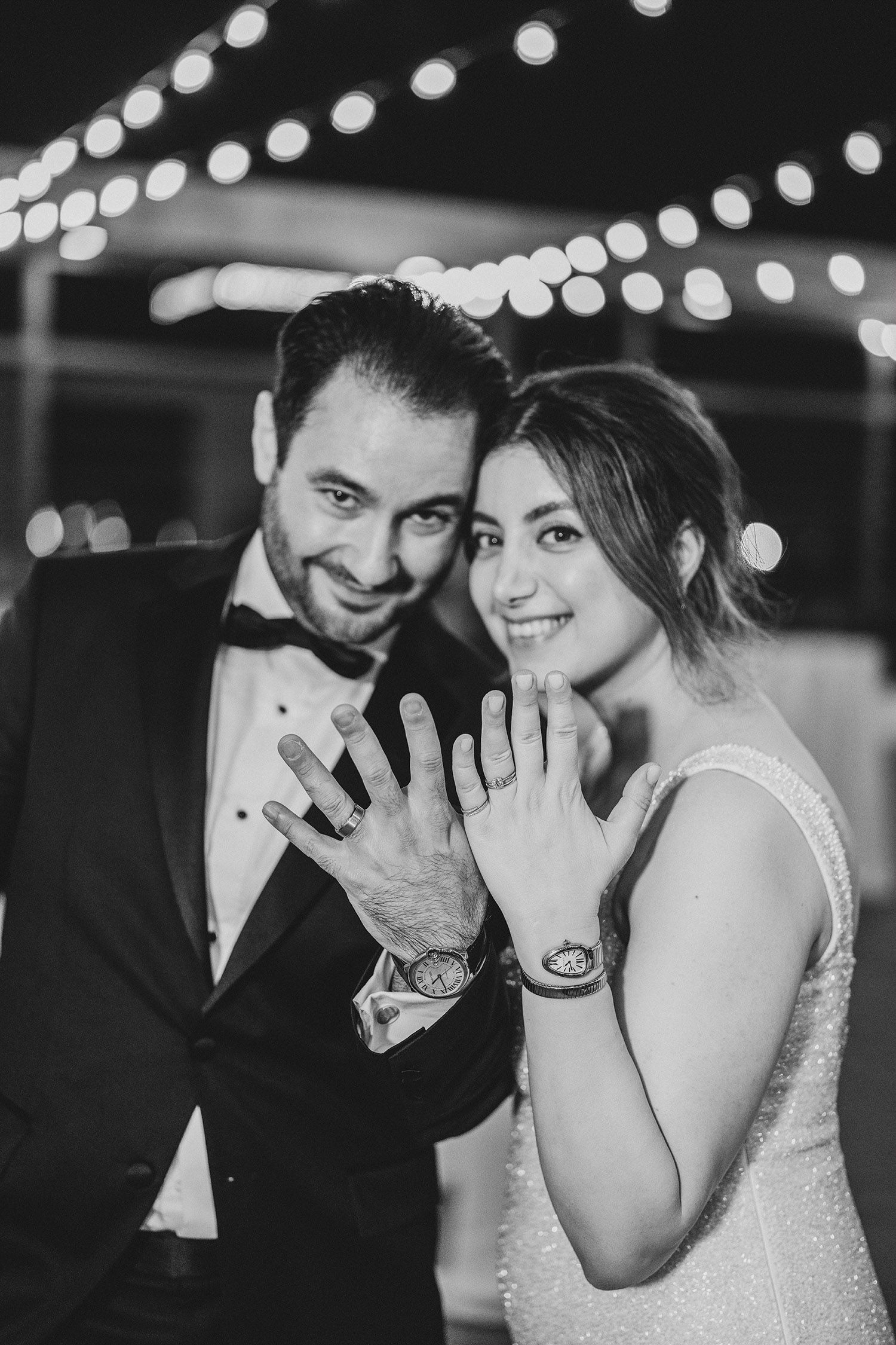 A black and white wedding photo sequence showing a couple sharing intimate laughing moments under string lights.