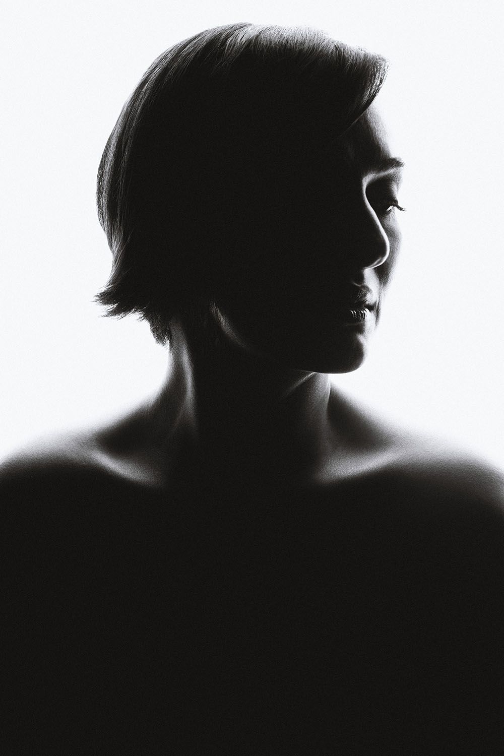 Black and white silhouette portrait of a woman with short hair against a bright white background.