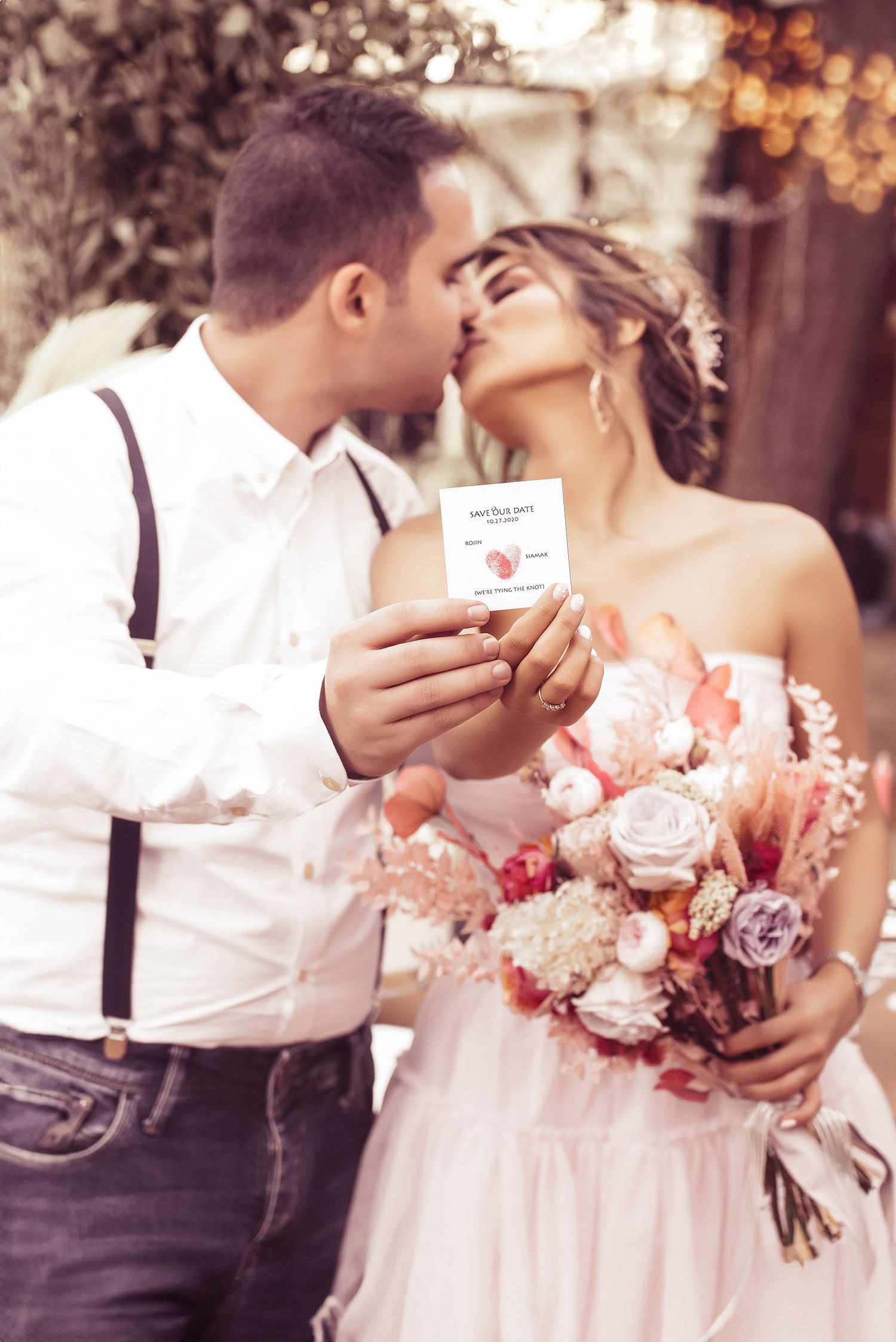 A romantic wedding couple shares tender moments while holding bouquets of pink and purple flowers in a dreamy outdoor setting.