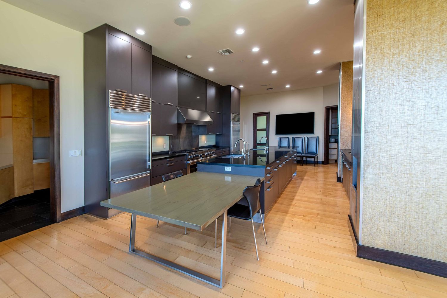 Modern apartment kitchen with stainless steel appliances, hardwood floors, and a sleek glass dining table.