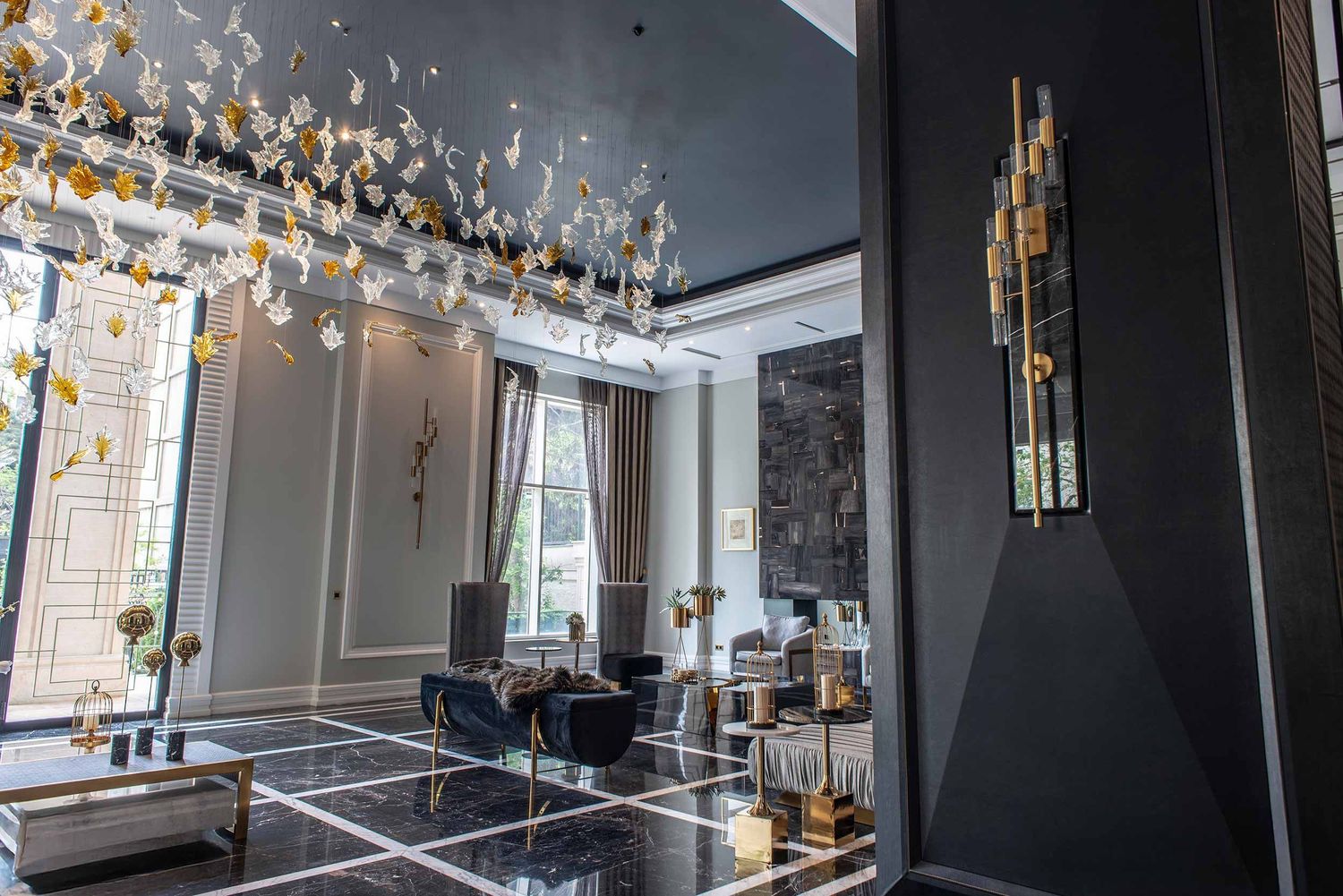 Modern luxury dining room with crystal chandelier, glass dining table, and elegant gold wall sconces in dark interior setting.