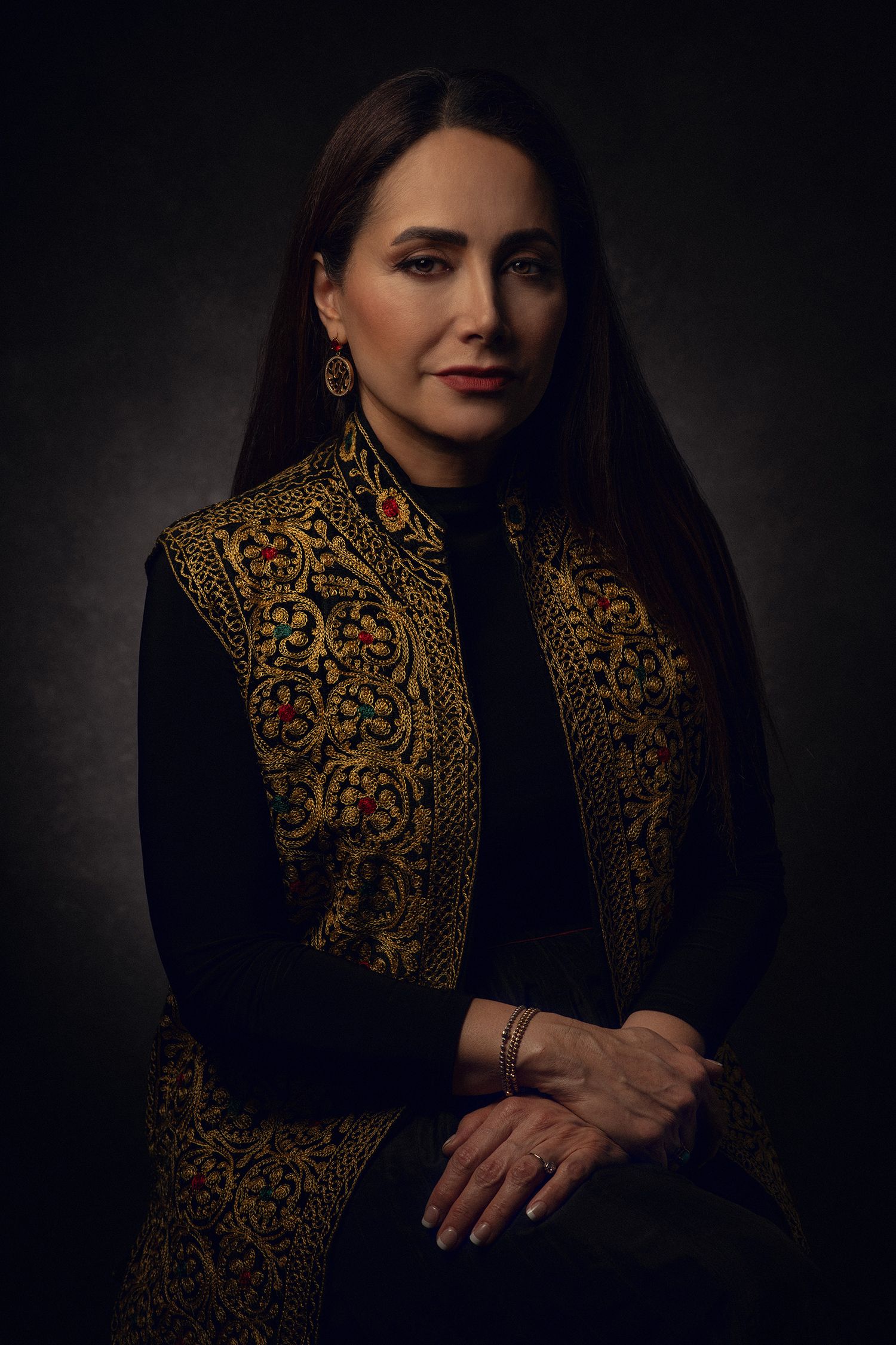 Professional portrait series of Iranian singer Mojgan Shajarian showing precious gold embroidered black jacket against dark background.