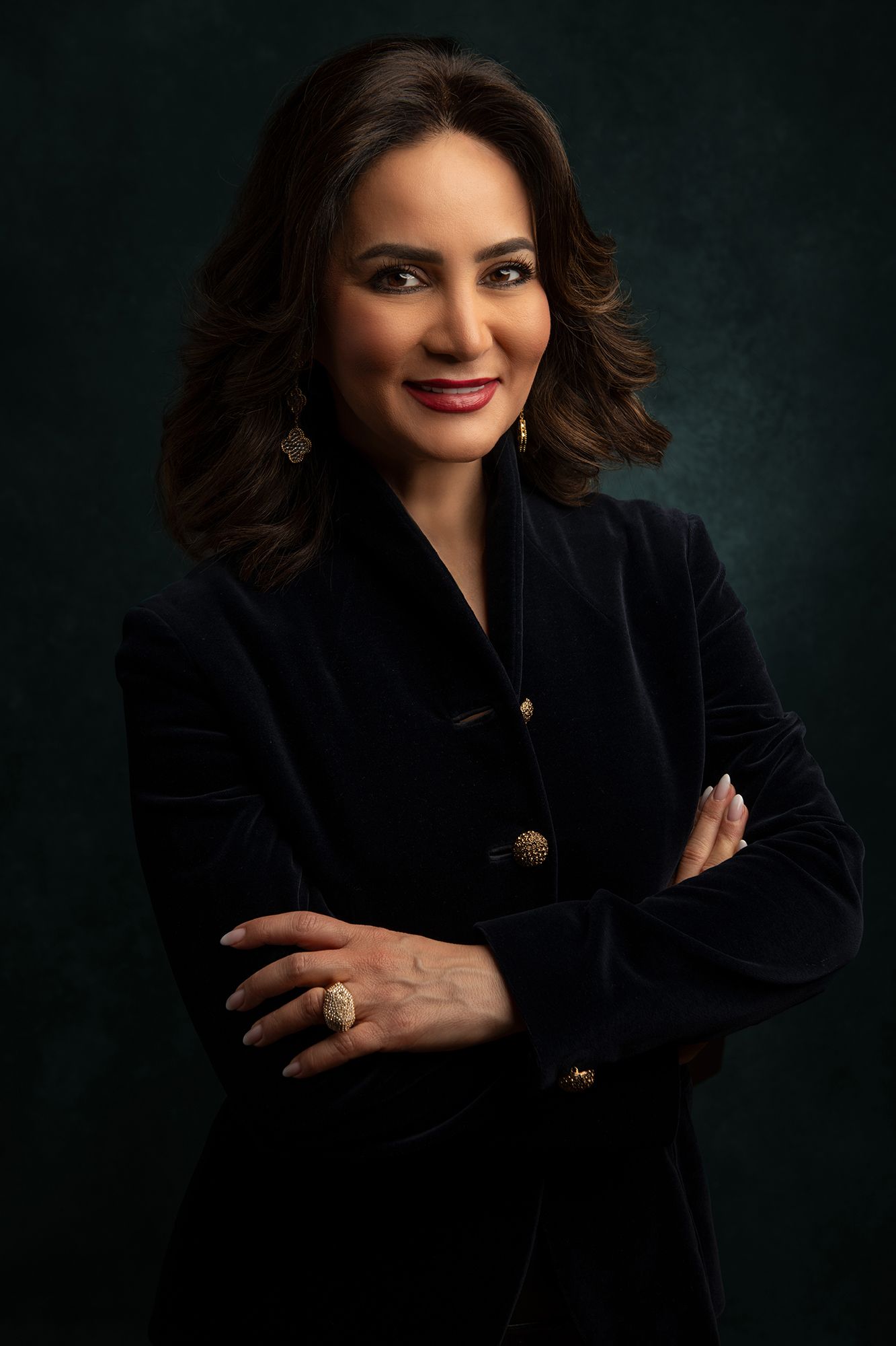 Professional portrait of entrepreneur Bita MIlanian in black velvet blazer with gold buttons against dark background in west Los Angeles.
