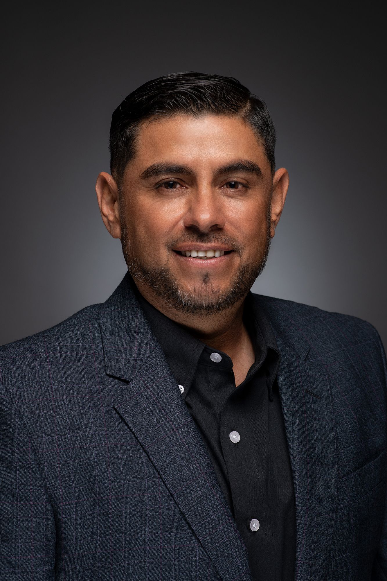 Corporate headshot and portrait of a professional in a dark blazer and black shirt against gradient backdrop taken in west Los Angeles.