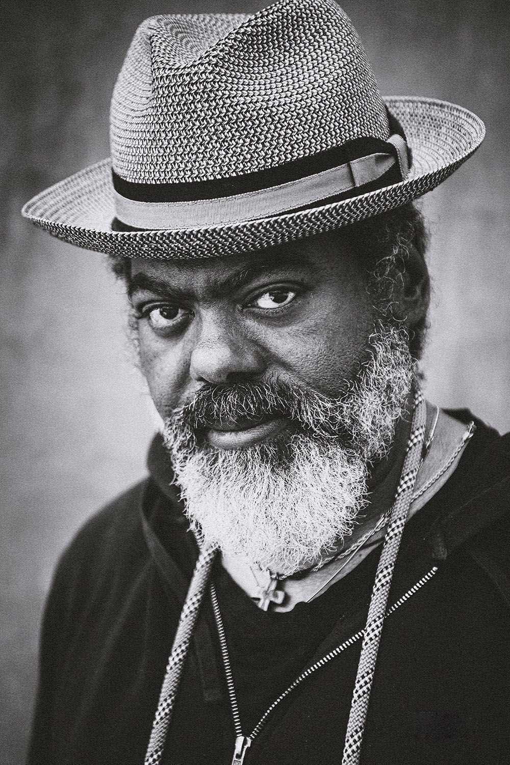 Black and white portrait of a bearded man wearing a straw fedora hat.