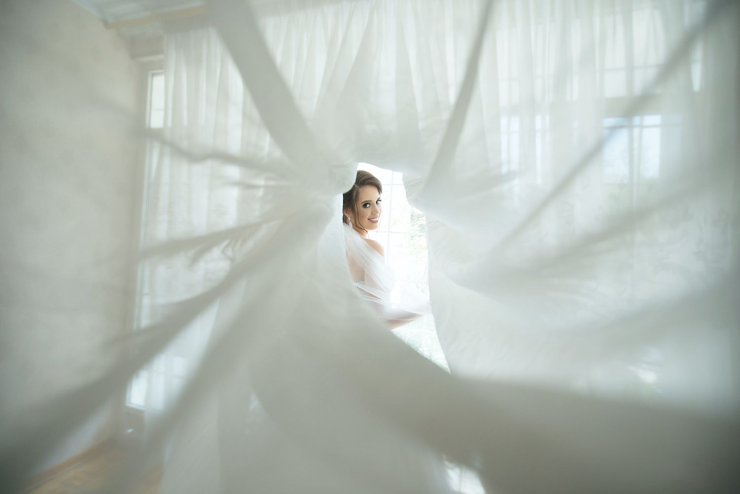 A dreamy bridal portrait sequence showing flowing white fabric and soft ethereal lighting through sheer curtains.