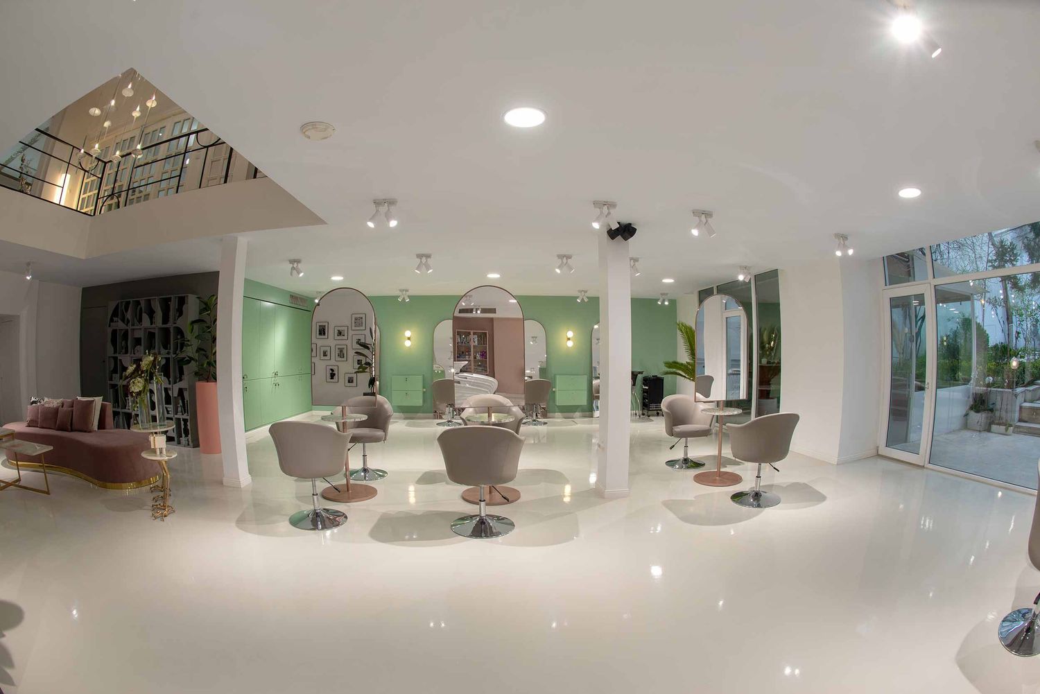 Modern hair salon interior with sleek styling stations, green accent walls, and glossy white floors under recessed lighting.