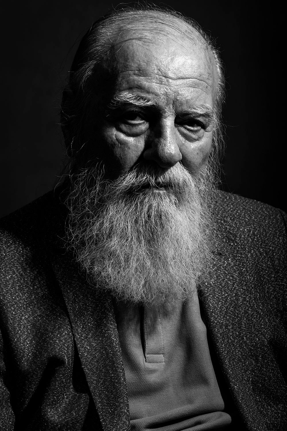 Black and white portrait of elderly man with long white beard and weathered face.