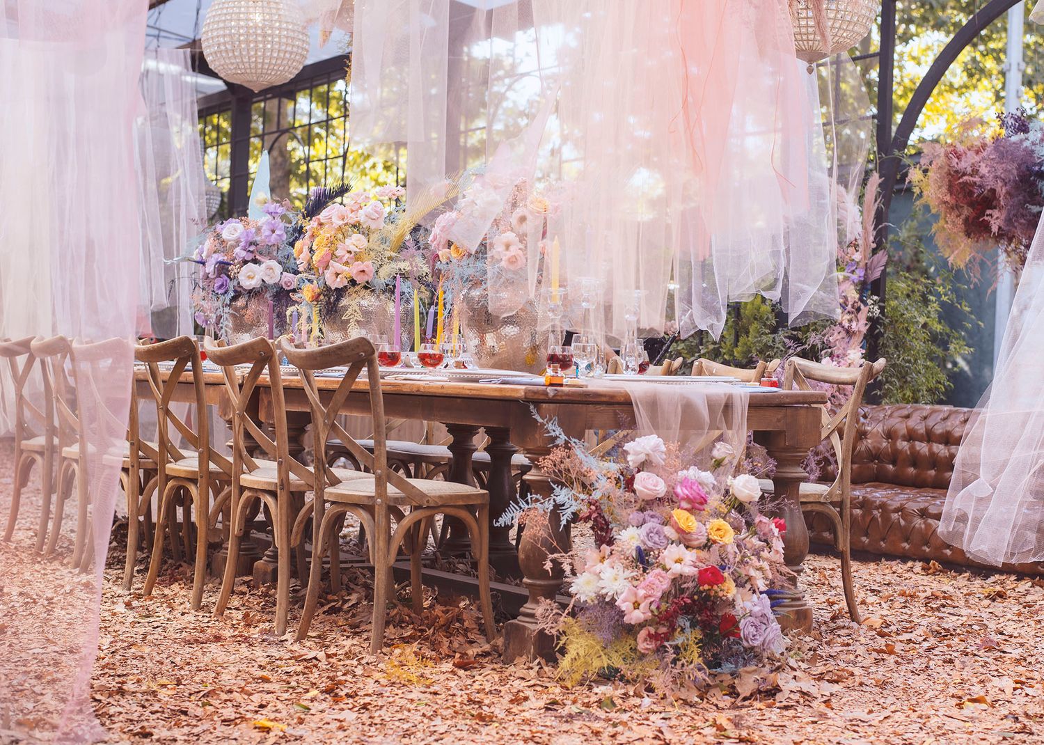 Rustic outdoor wedding reception setup with wooden chairs and floral arrangements in a dreamy autumn forest setting.
