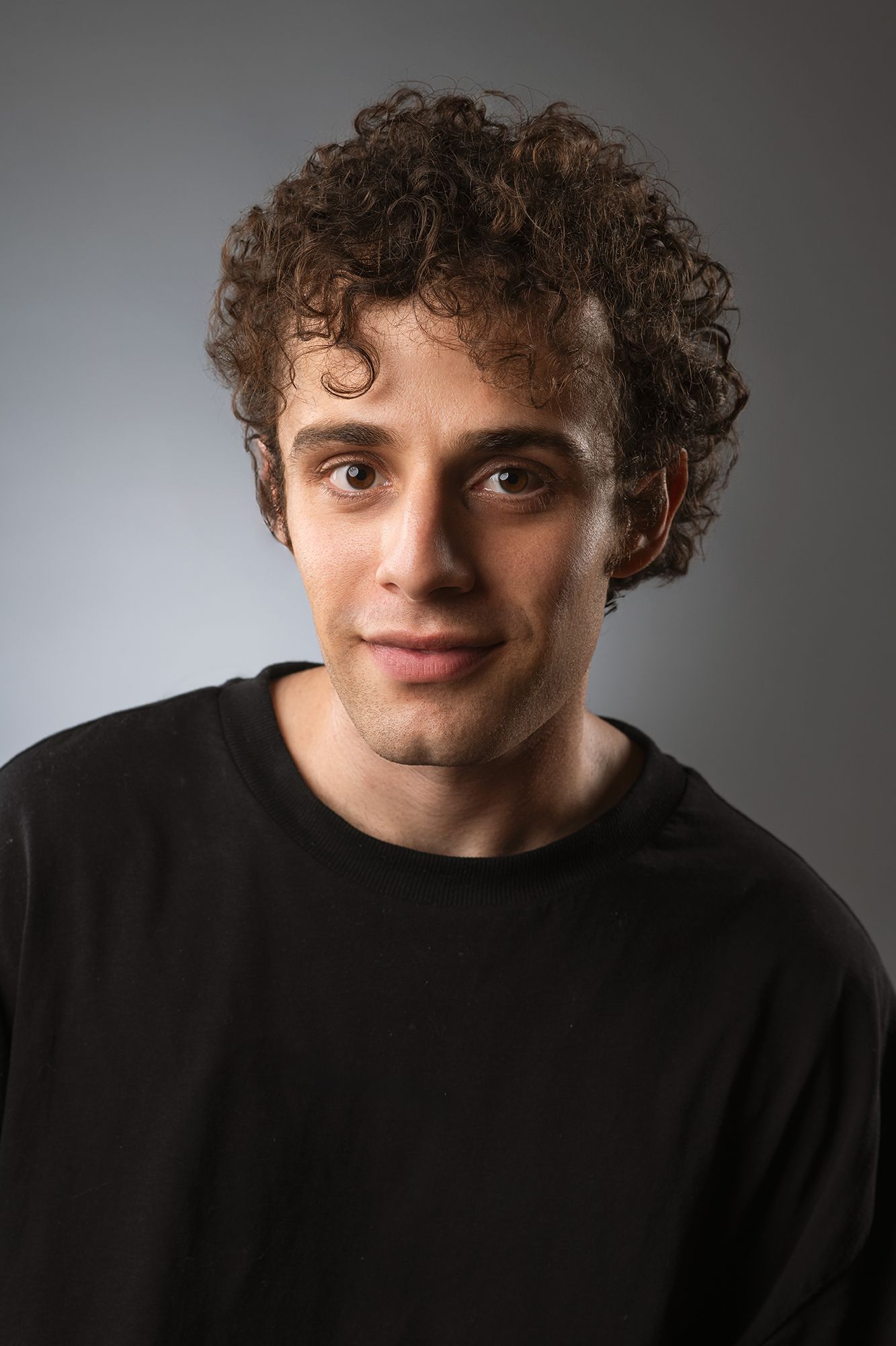 Portrait and headshot series showing person with curly hair in black shirt against grey backdrop taken in west Los Angeles.