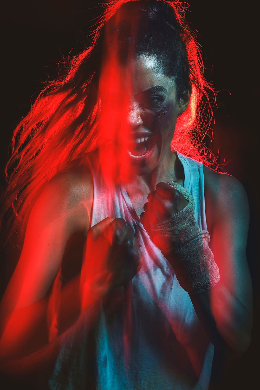 Female boxer with wrapped hands in fighting stance, dramatic red and teal lighting with motion blur effect.