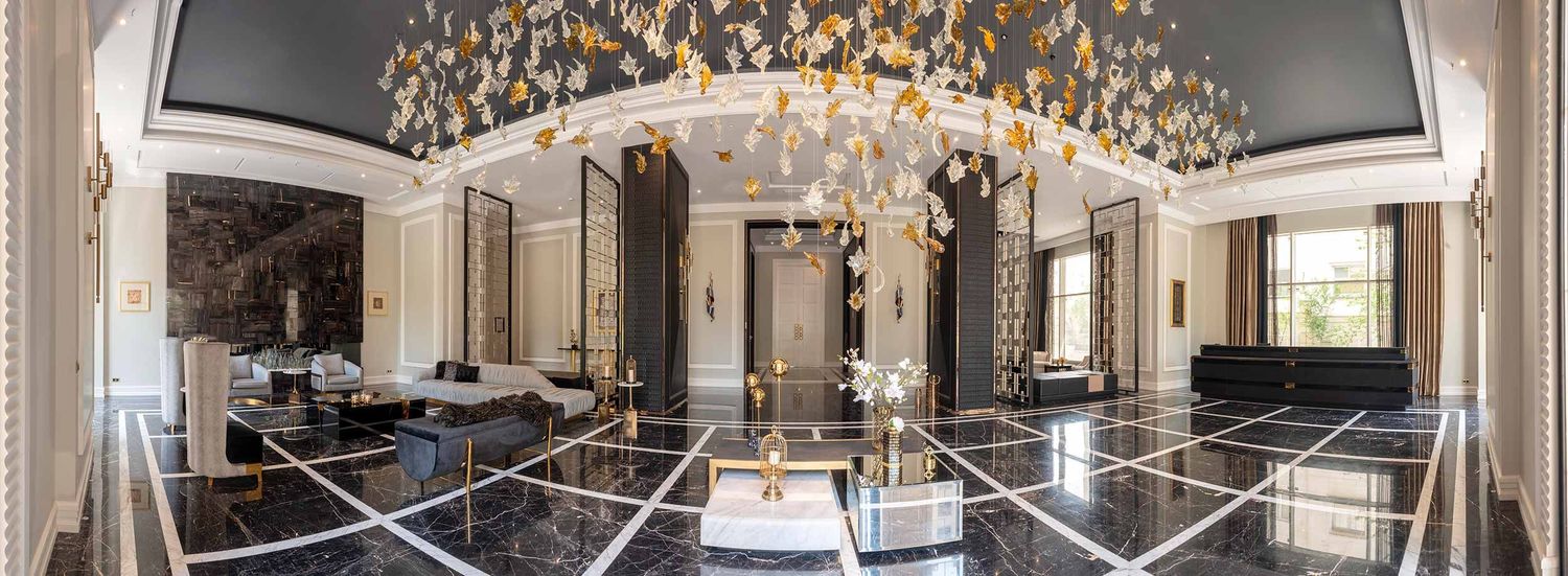 Panoramic view of an elegant grand ballroom with crystal chandeliers and ornate gold detailing on the walls and ceiling.