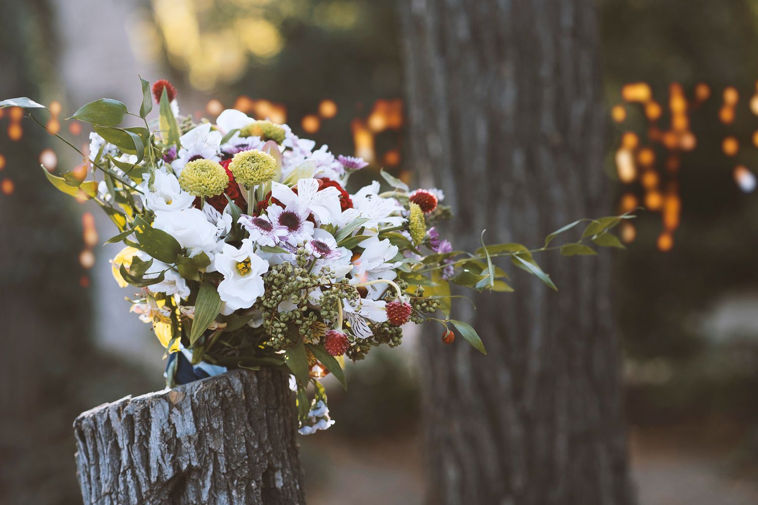 White orchids and burgundy flowers arranged in rustic wooden vases create an elegant table centerpiece display.