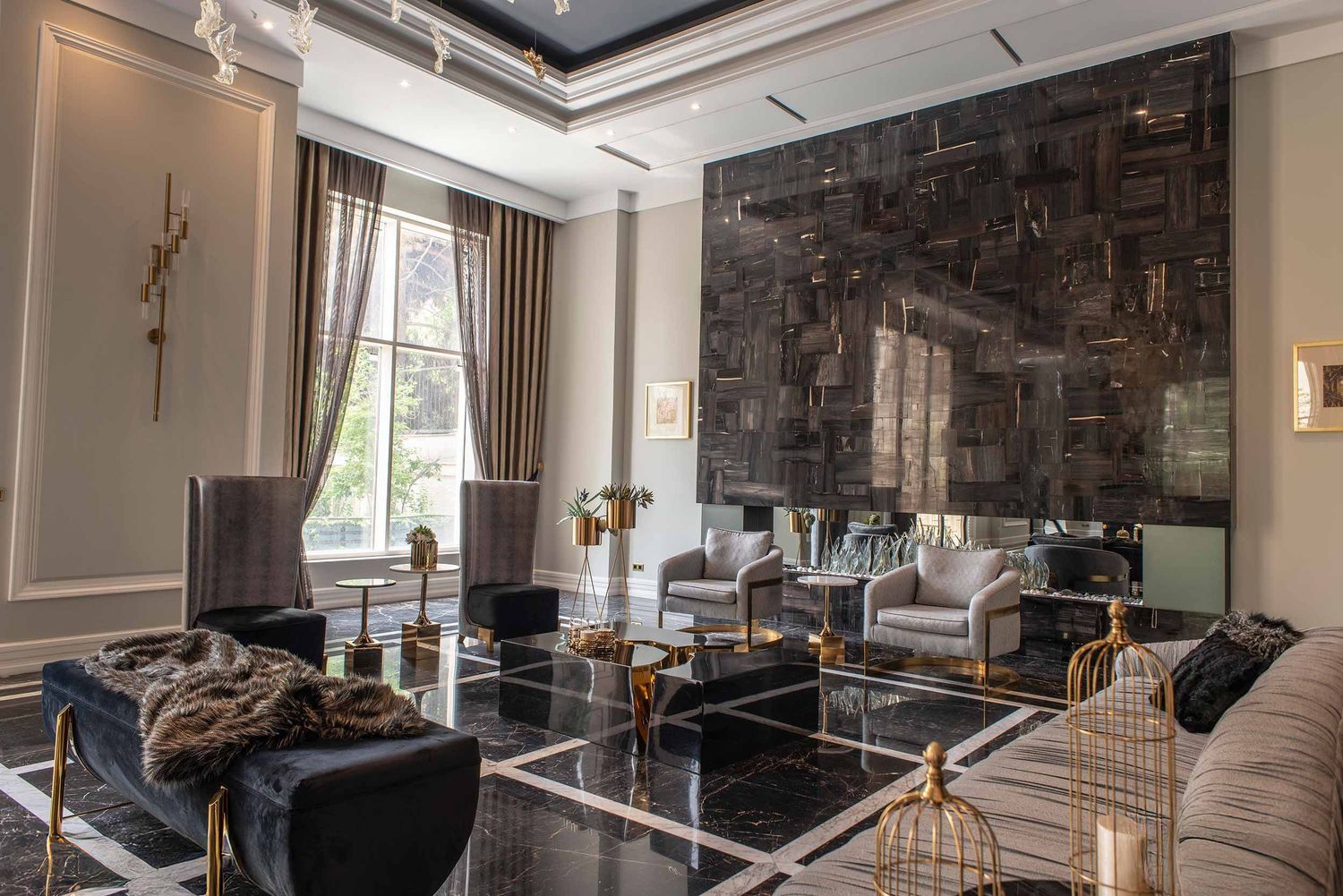 Luxurious modern living room with dark stone feature wall, glass coffee table, and elegant beige and gold accents.