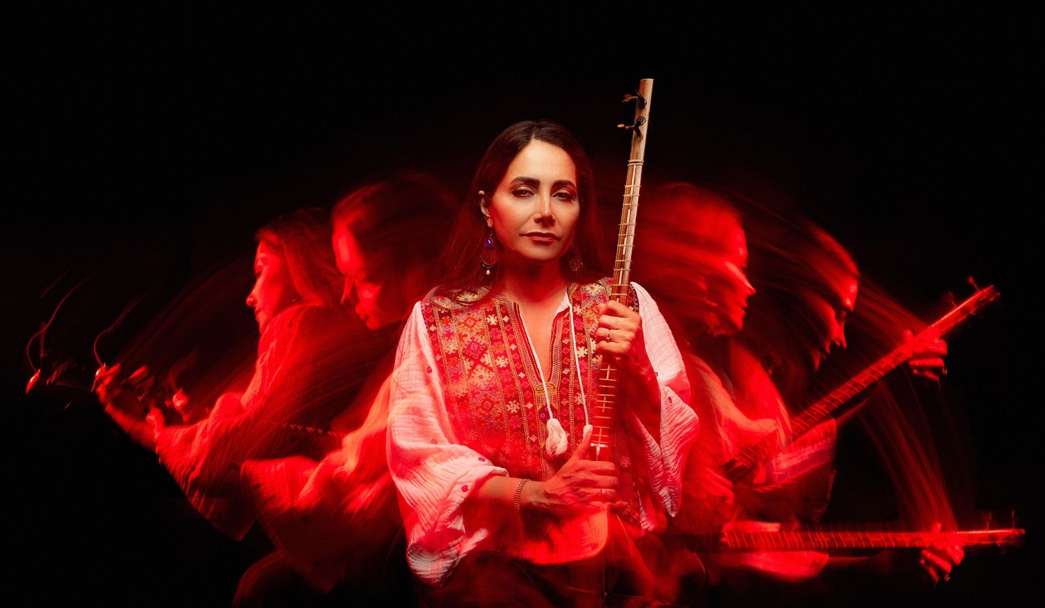 Dramatic portrait of Iranian musician and singer Mojgan Shajarian with sitar surrounded by red light effects taken in Westwood Los Angeles.