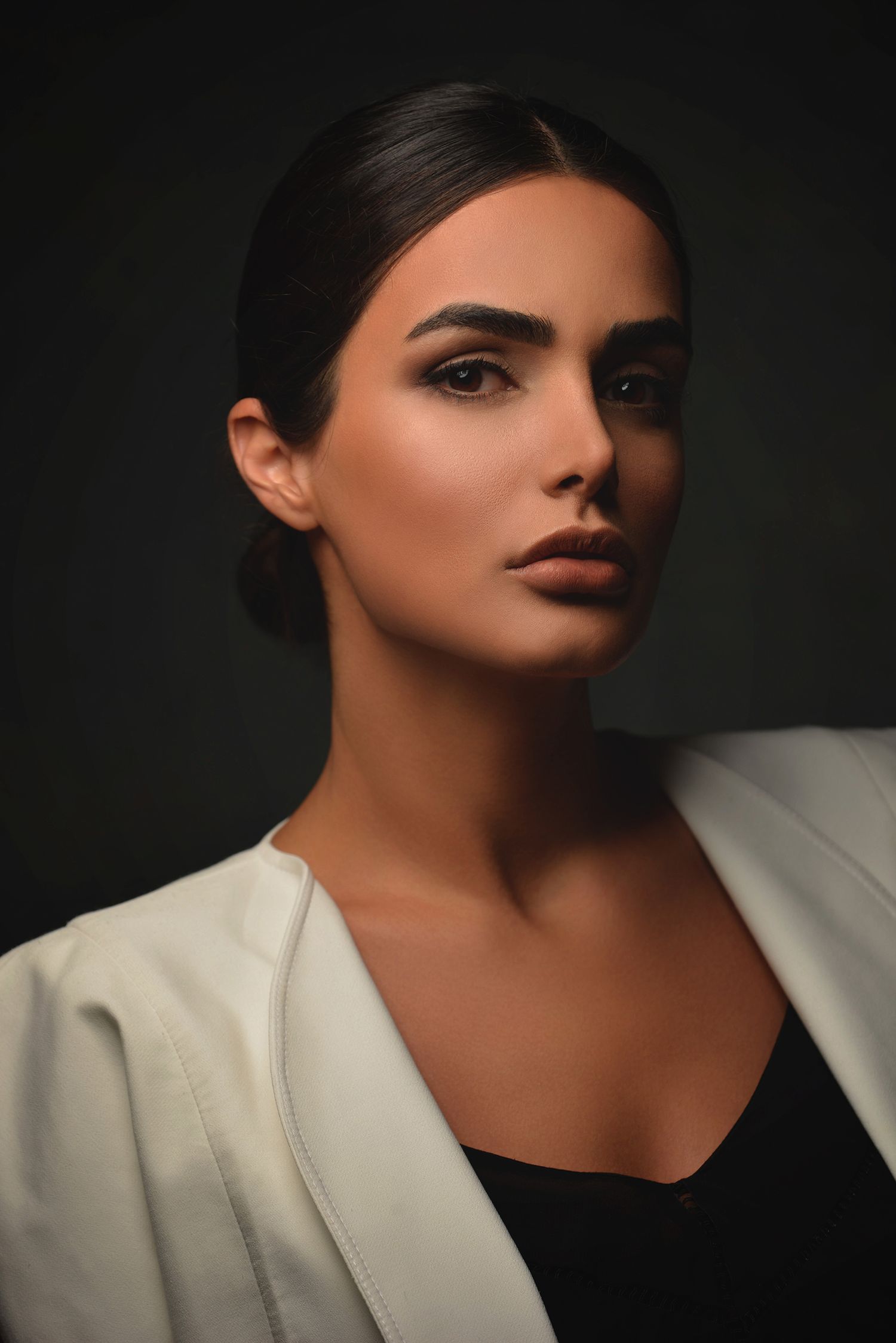 Dramatic portrait of model in white blazer with striking makeup against dark background taken in westwood Los Angeles
