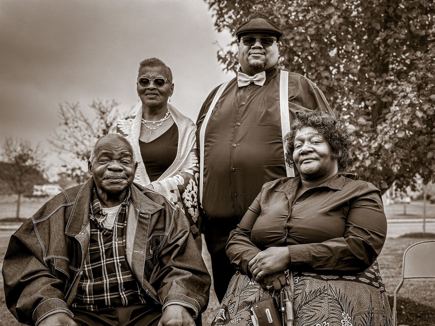 Group portrait of people smiling together outdoors in black and white.