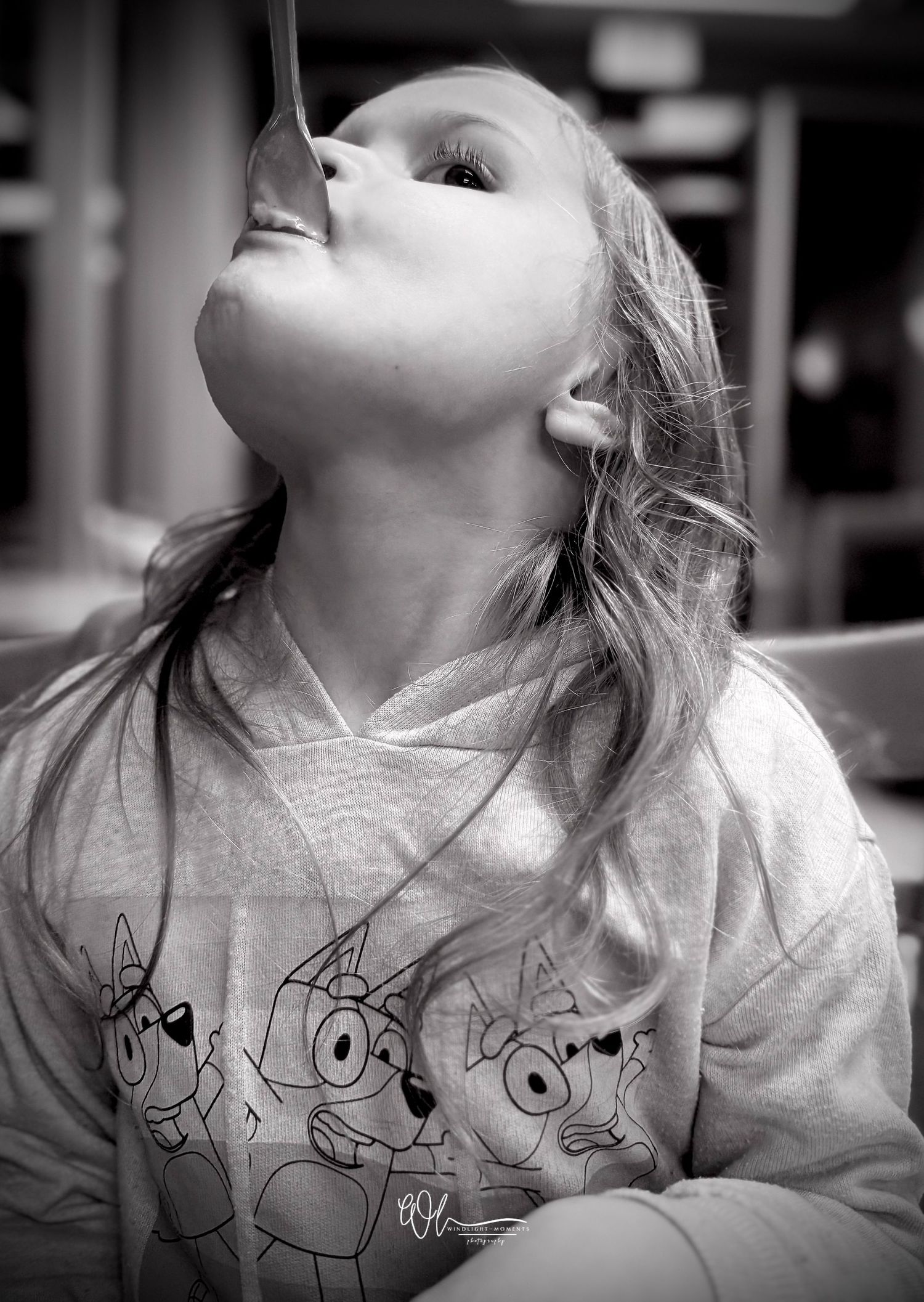 A black and white photo series shows a child wearing a sweatshirt with cartoon character drawings looking upward.