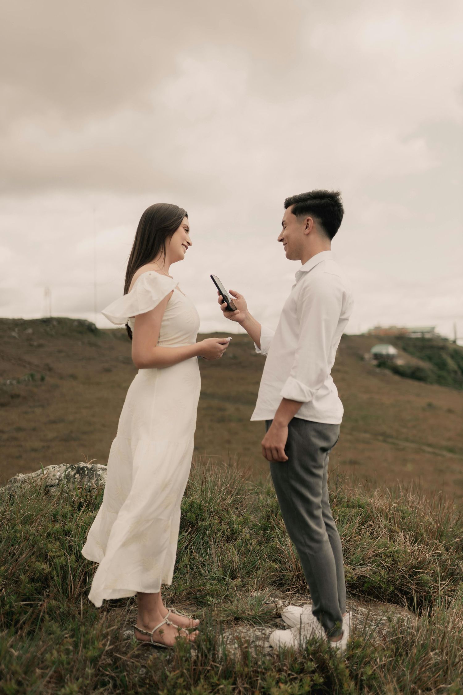 Couple sharing a romantic moment on hilltop during proposal.