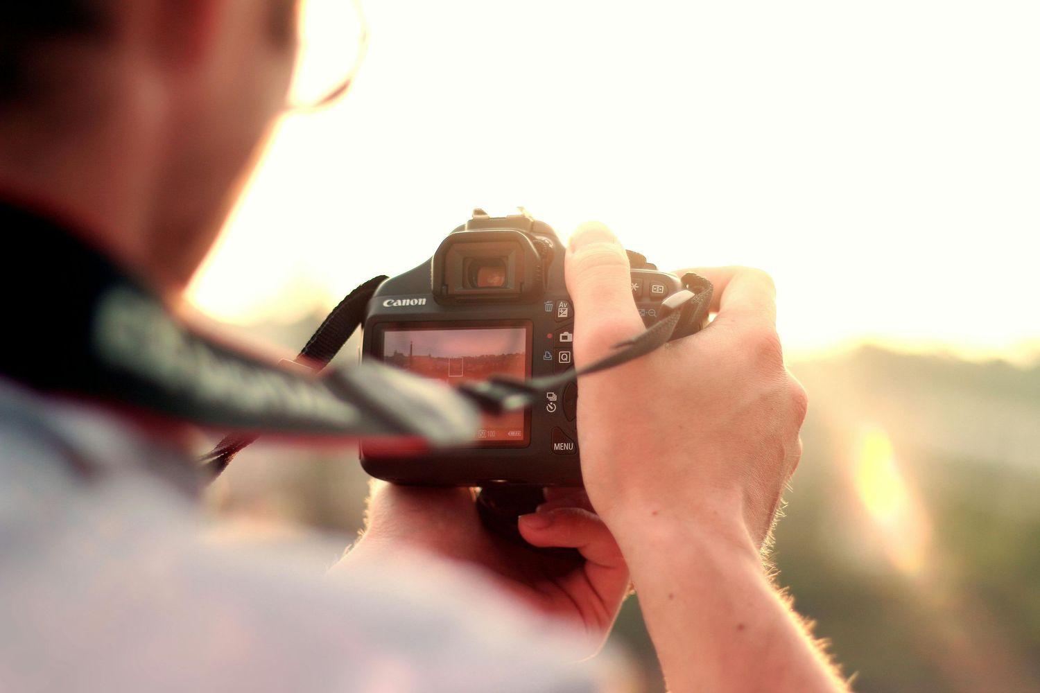 Camera lens silhouetted against a golden sunset sky.