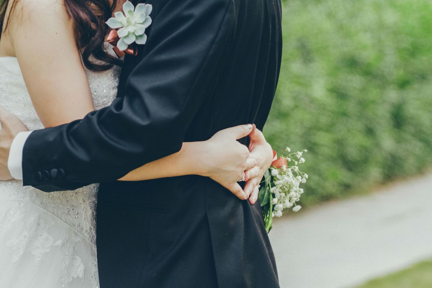 Close-up of a couple embracing in formal attire during an outdoor photoshoot.