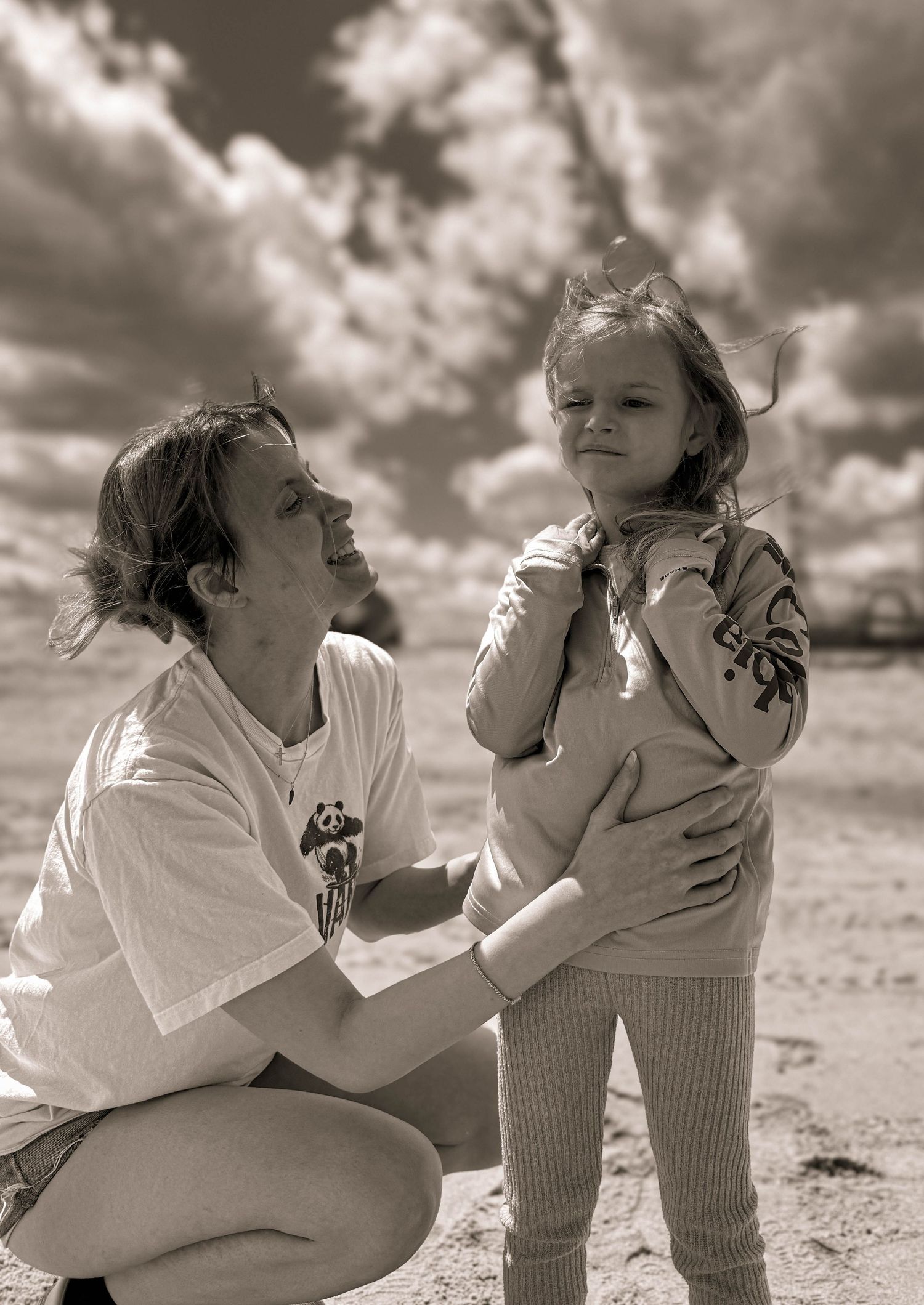 Black and white photograph showing tender moments on a beach.