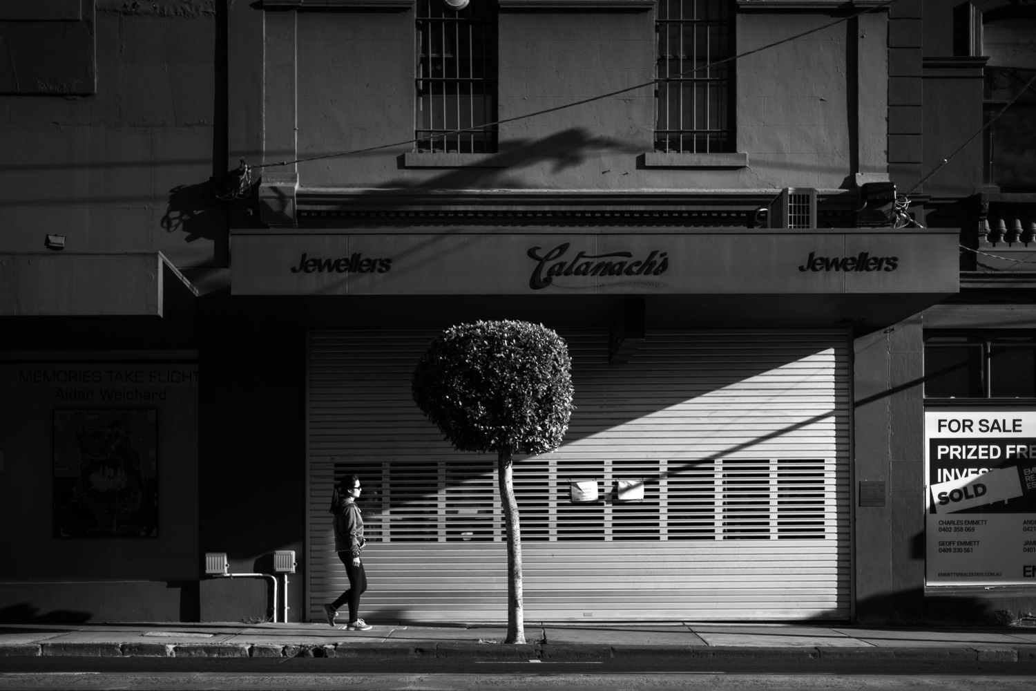 Black and white architectural photograph of a storefront with closed shutters.