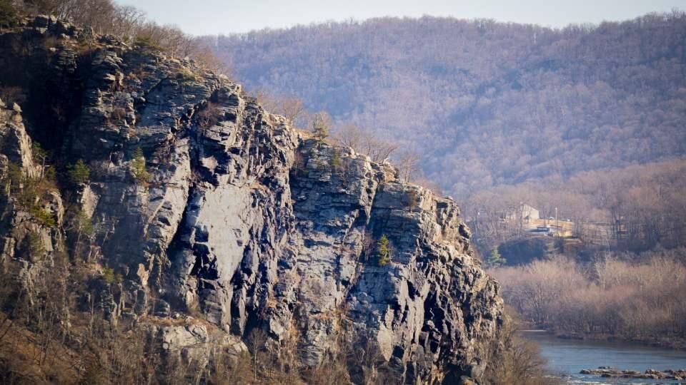 Rocky cliffs and mountains rise above a winding river valley in the distance.