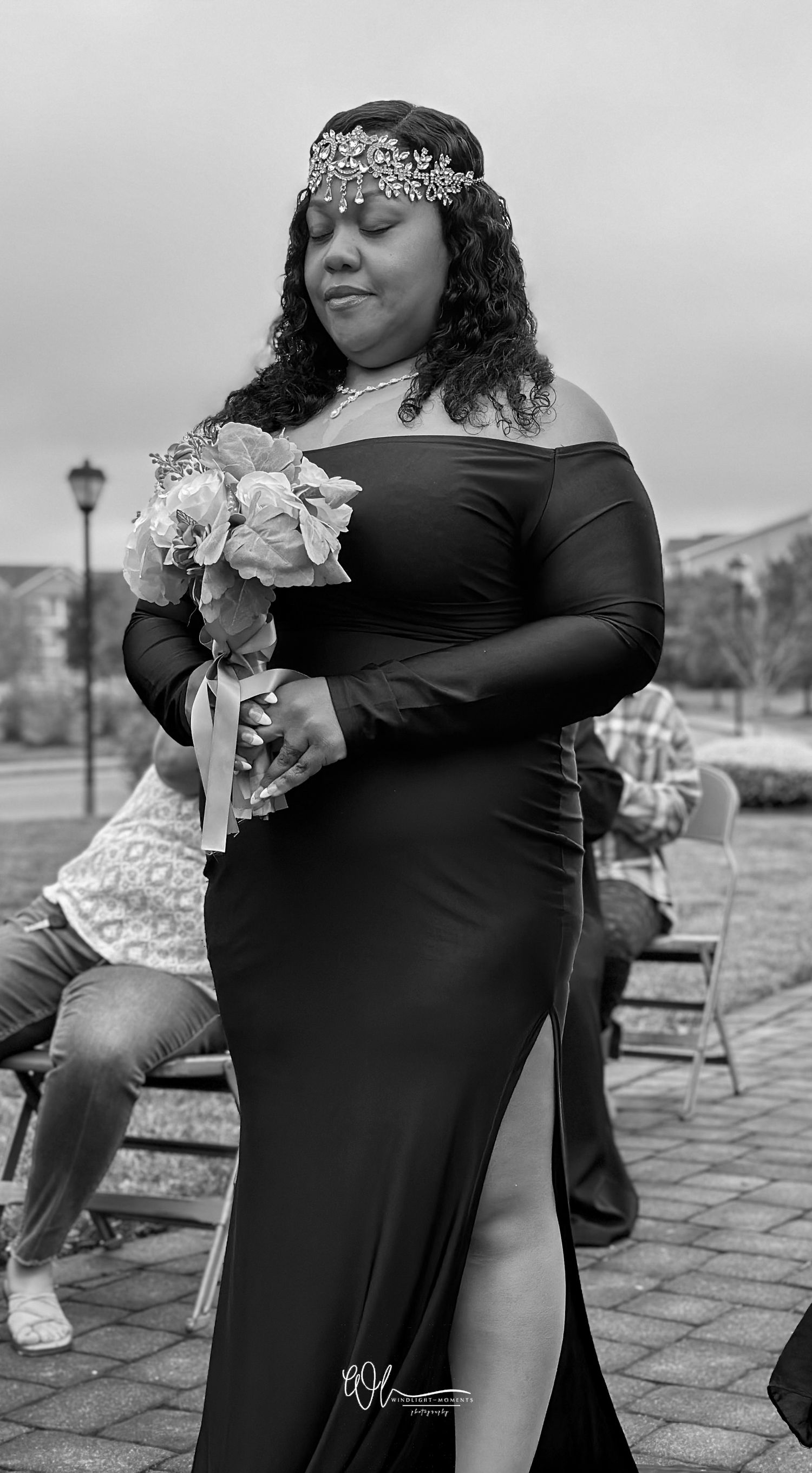 A series of black and white maternity photos showing a pregnant person in a black dress posing outdoors with flowers.