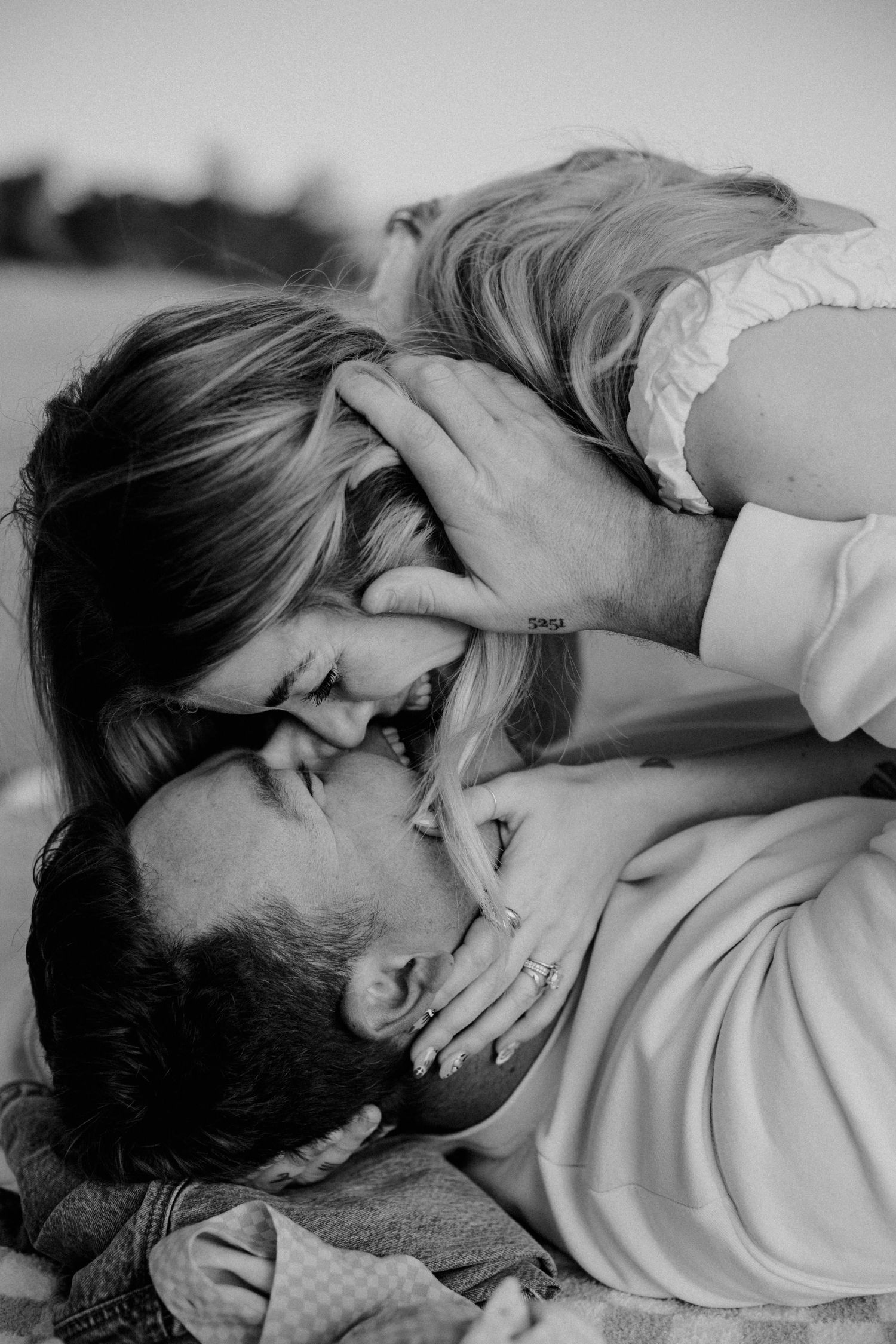 Two people share an intimate embrace while lying down in black and white photography.