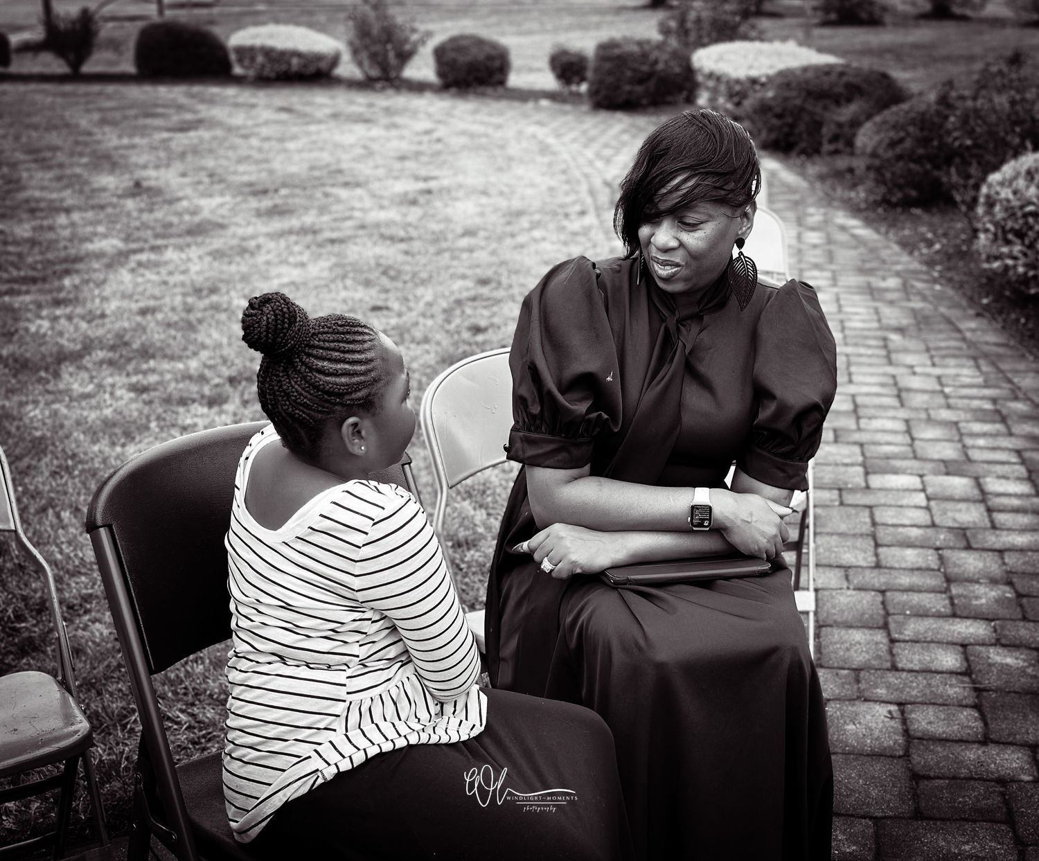 Black and white sequence of photos showing two people sitting on a bench in conversation, with one wearing stripes.