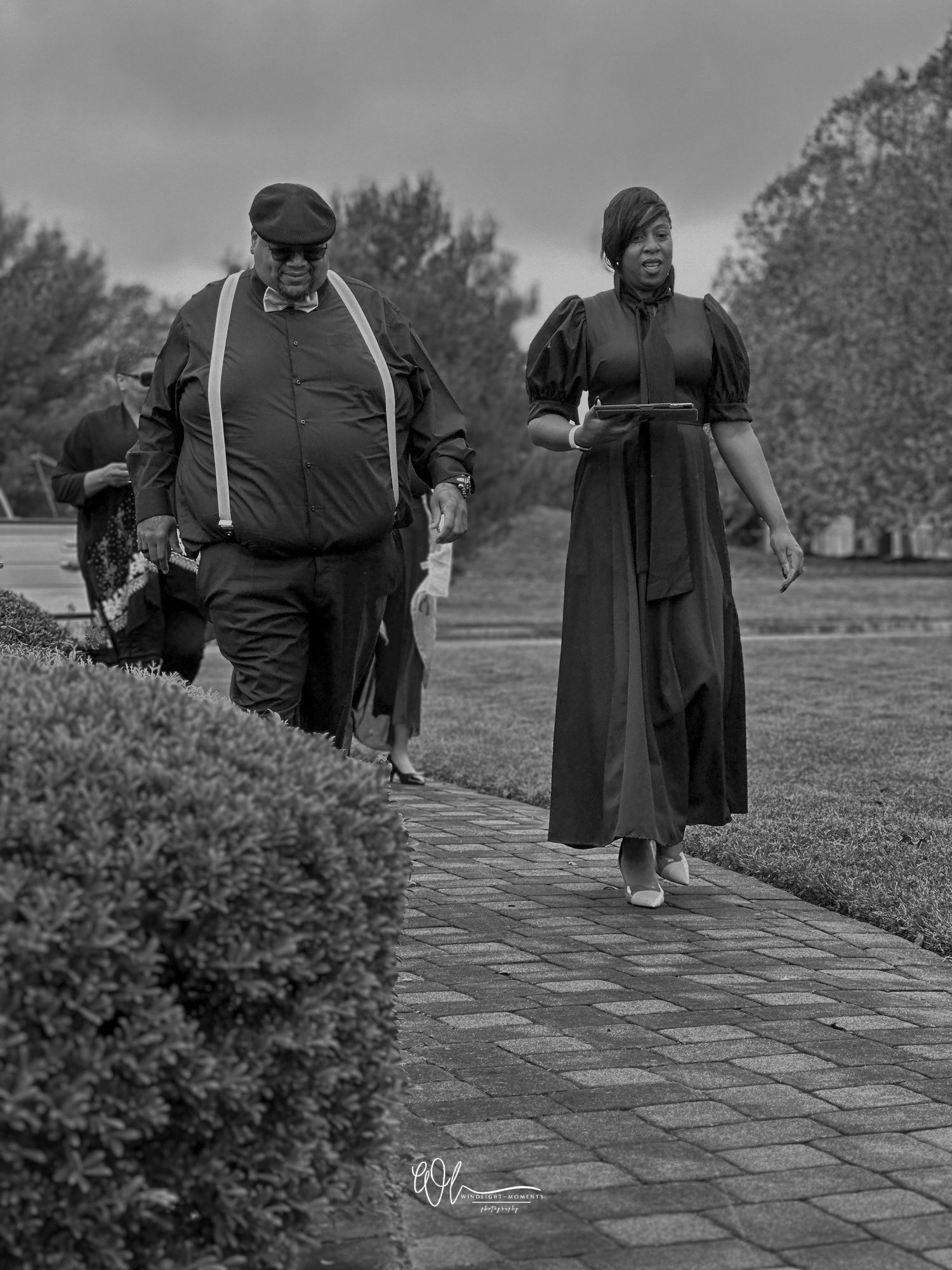 A sequence of black and white photos showing people walking along a stone path in an outdoor setting.