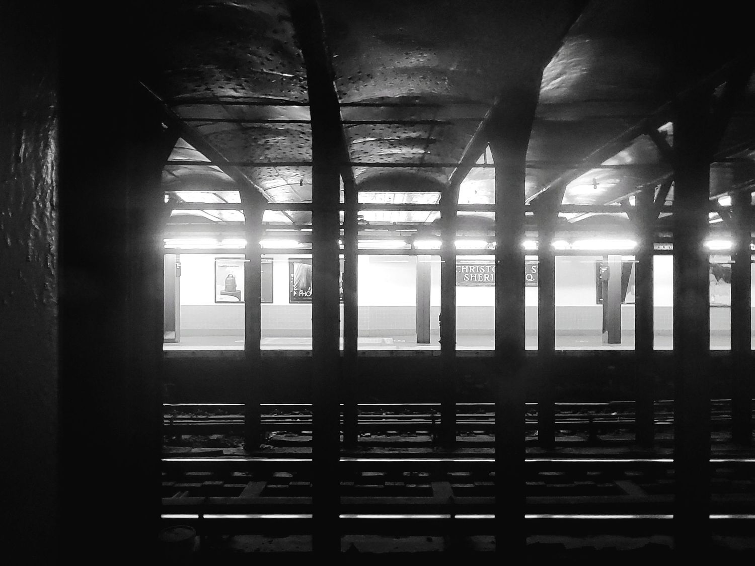 Dark industrial subway platform interior with dramatic lighting and repeating columns.