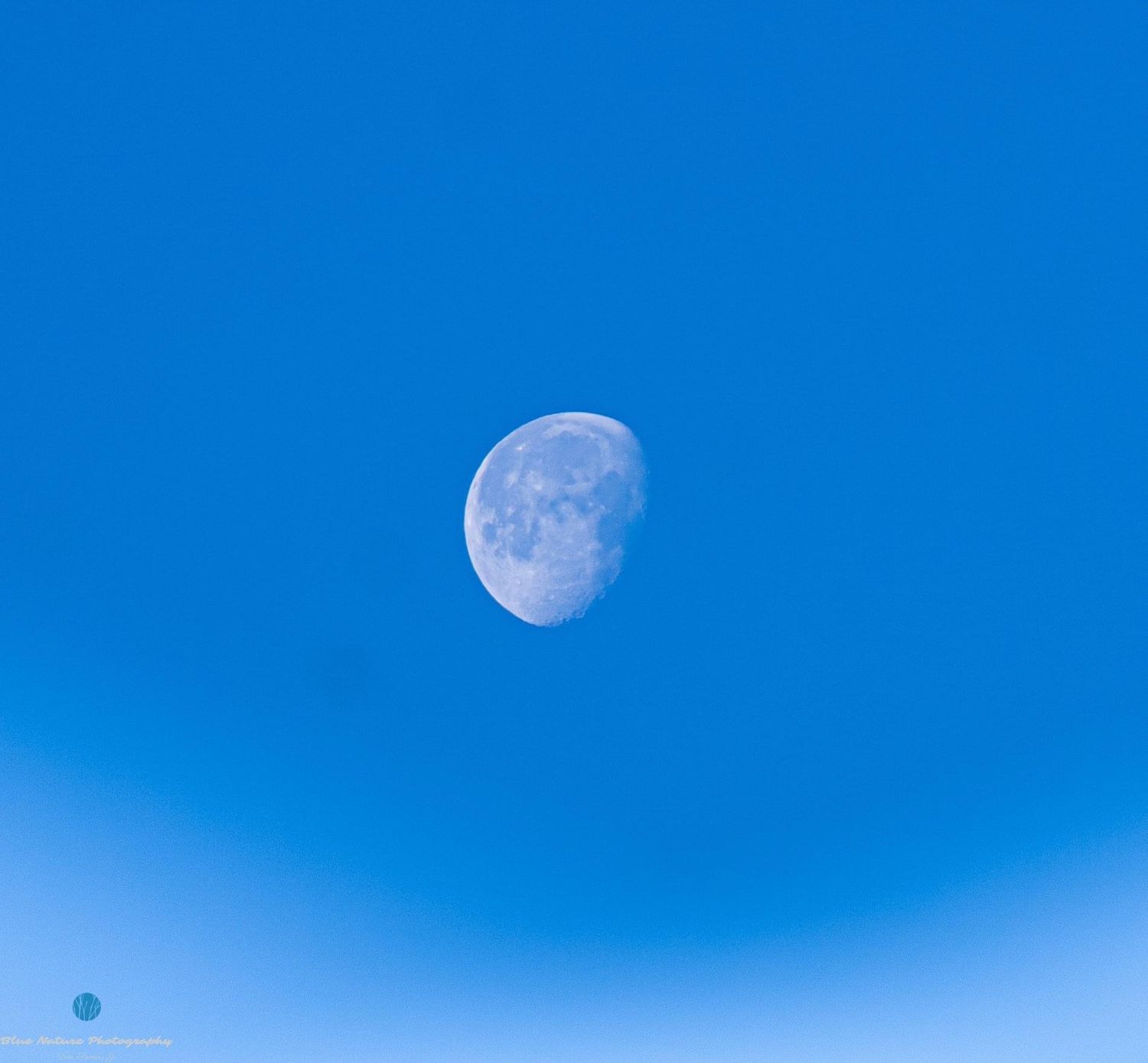 Sequence showing moon phases in bright blue sky during daytime.