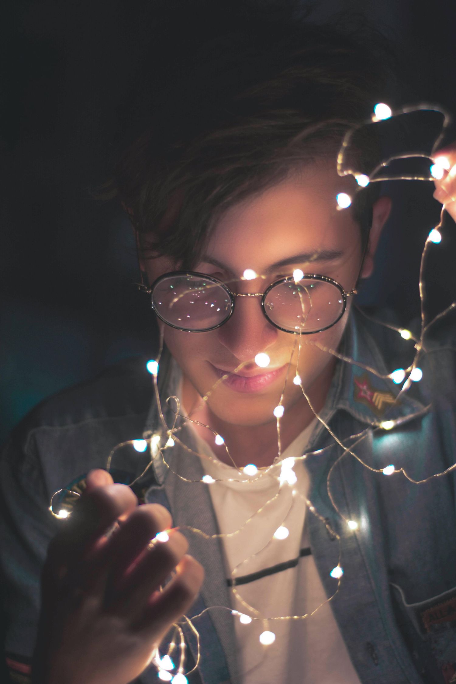 Person holding glowing fairy lights in the dark creating a magical atmosphere.