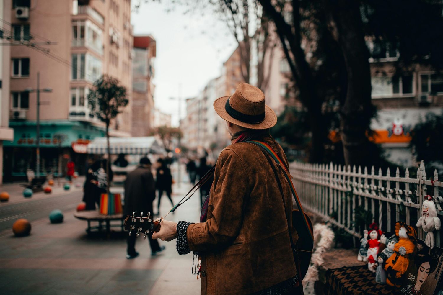 Person in brown coat walking along urban street with vintage buildings.