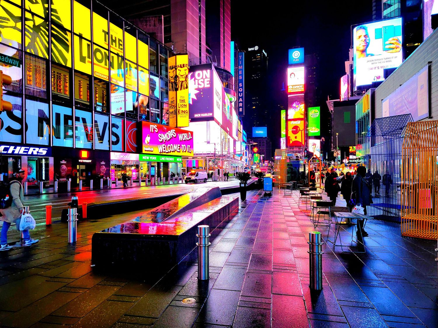 Vibrant nighttime panorama of Times Square with neon signs and bright LED displays.