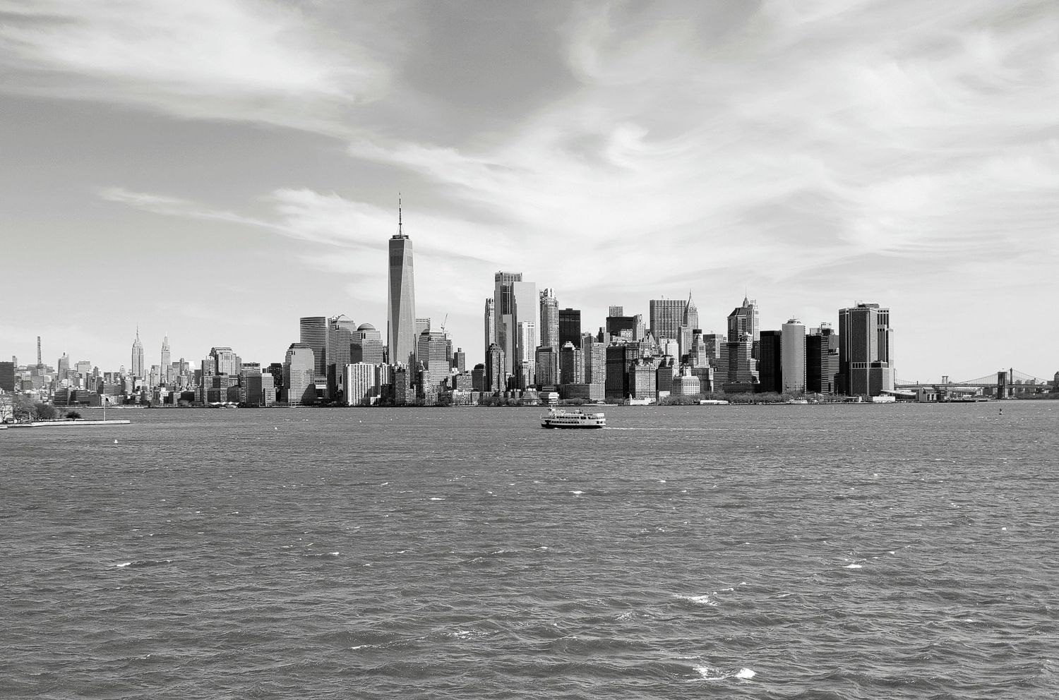 Panoramic black and white skyline view of Manhattan across the water with dramatic cloudy sky.