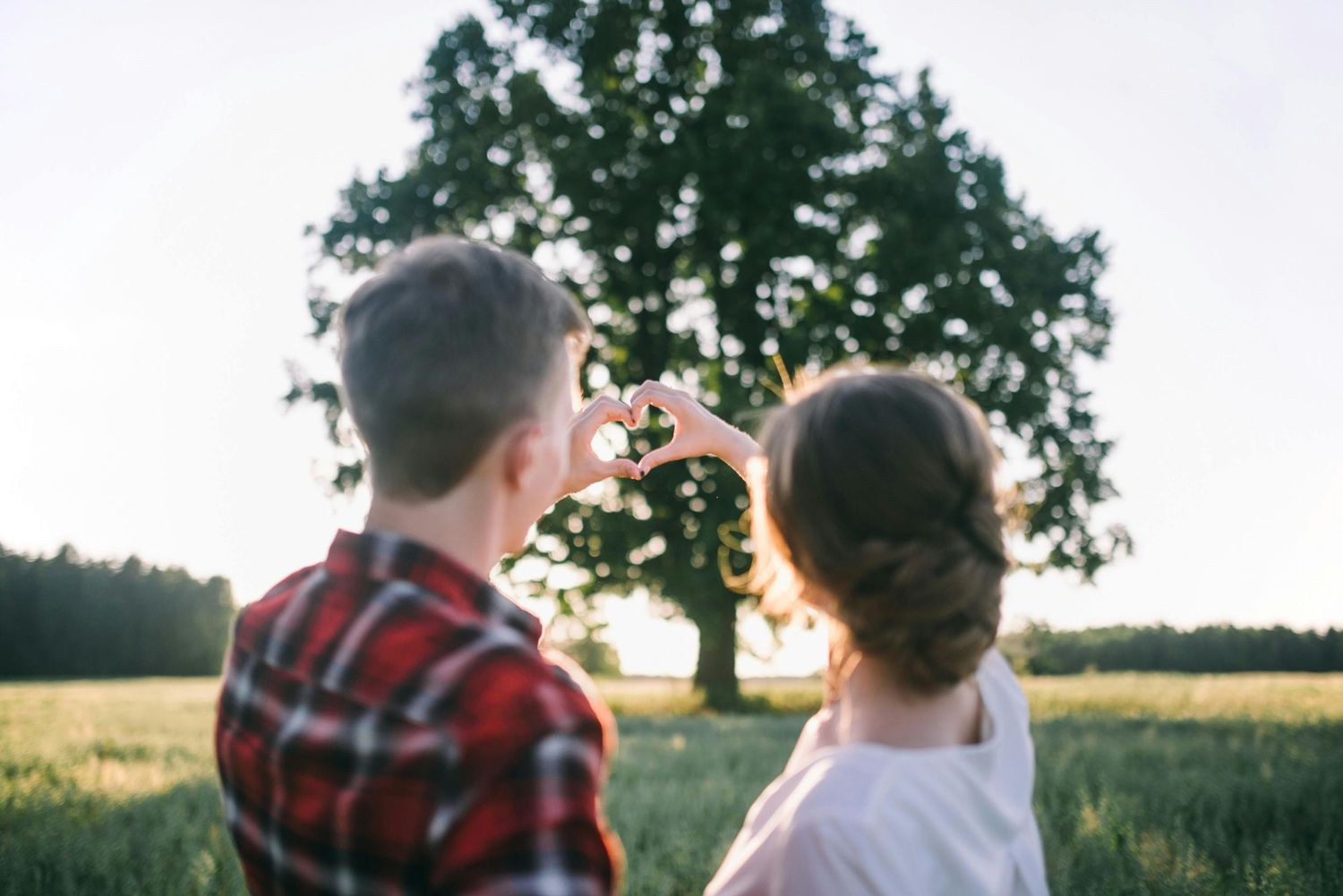 A couple enjoys a romantic moment together in a rural field at sunset.