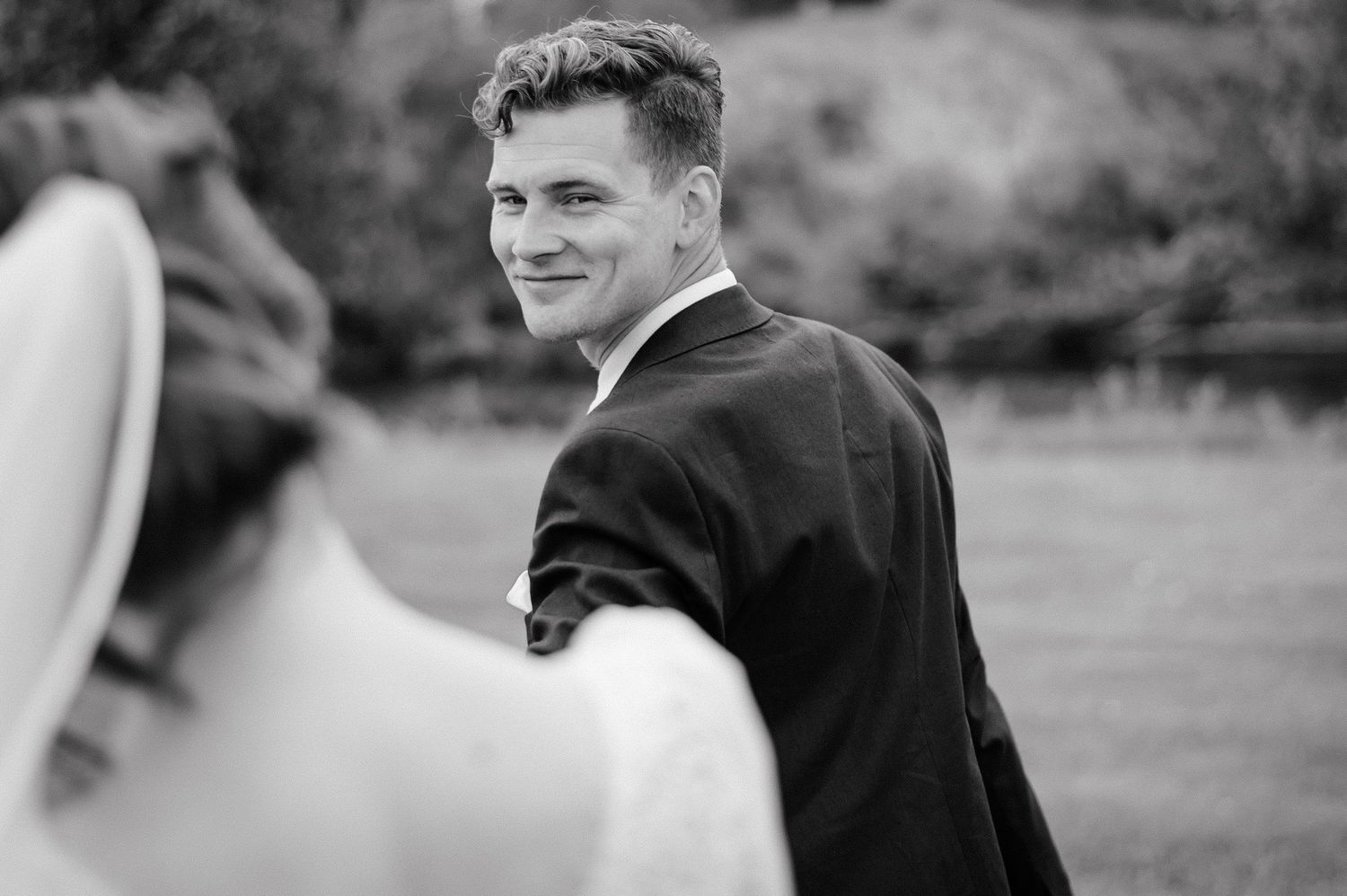Black and white picture where groom looking back on the bride.
