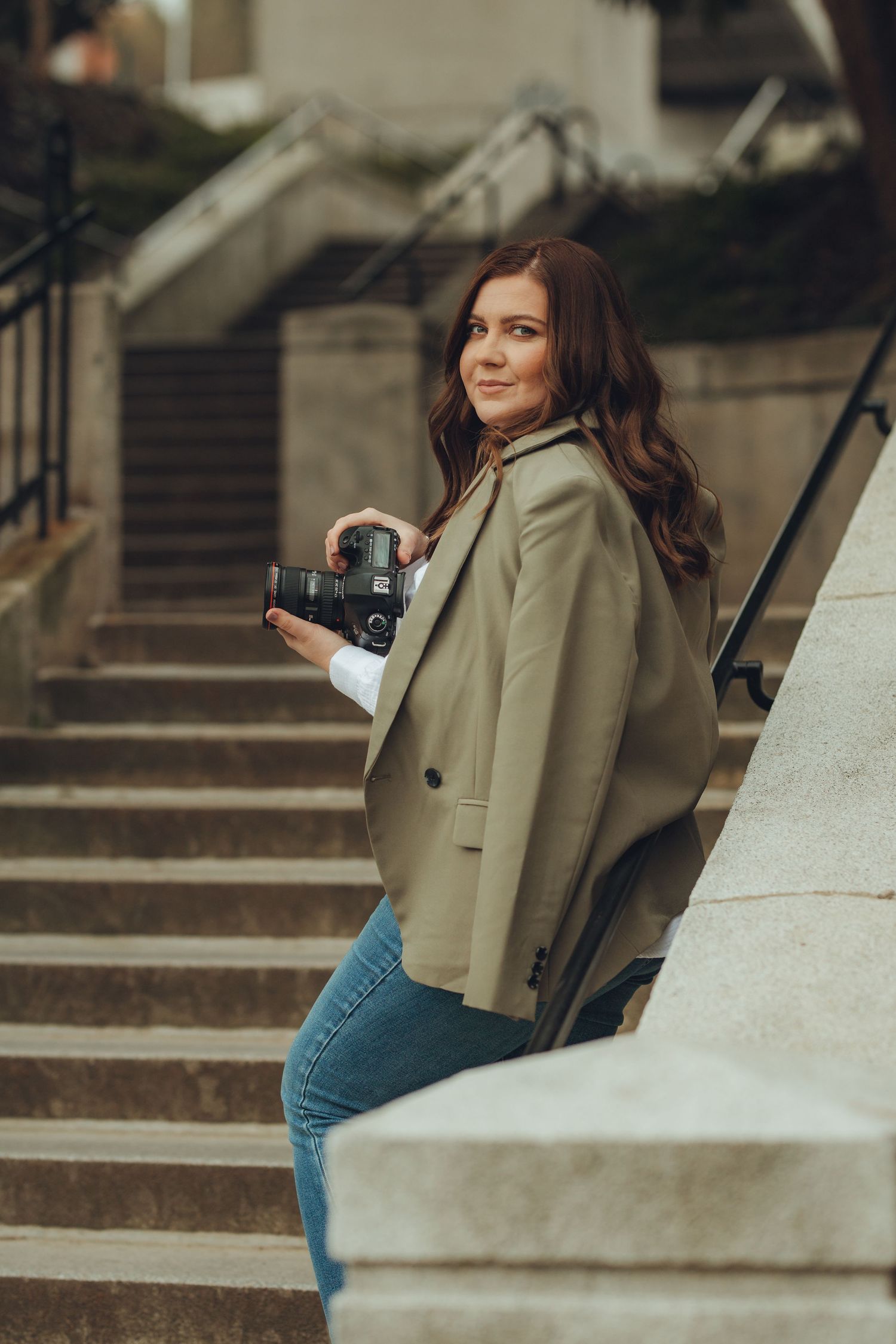 Casual photoshoot on concrete steps featuring beige blazer and denim outfit.