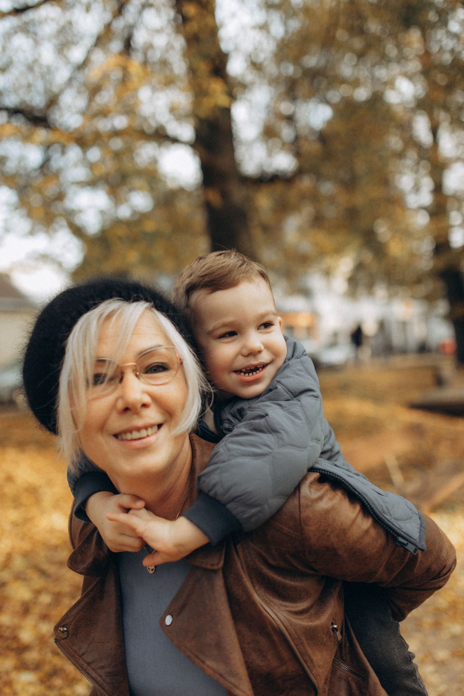 Playful piggyback ride scene captured in a fall park setting.