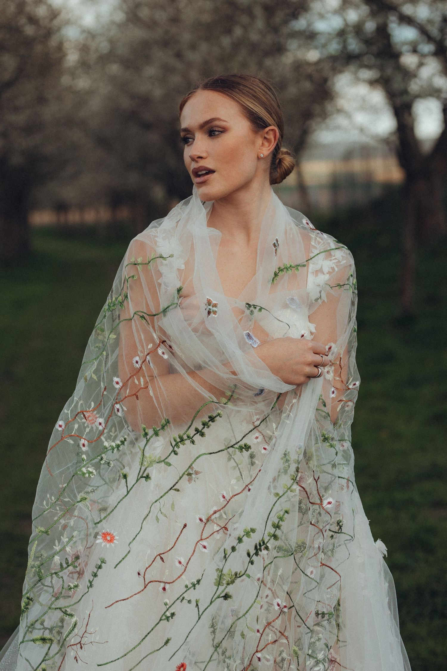 Close-up of delicate floral embroidery on a sheer wedding veil against a natural spring backdrop.