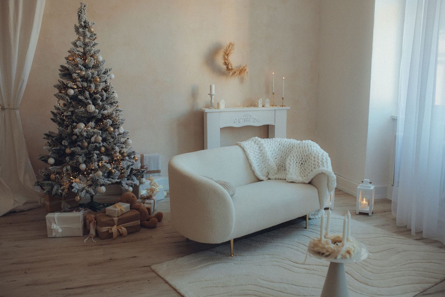 Minimalist white living room decorated for Christmas with a tree, sleigh decor, and soft window lighting.