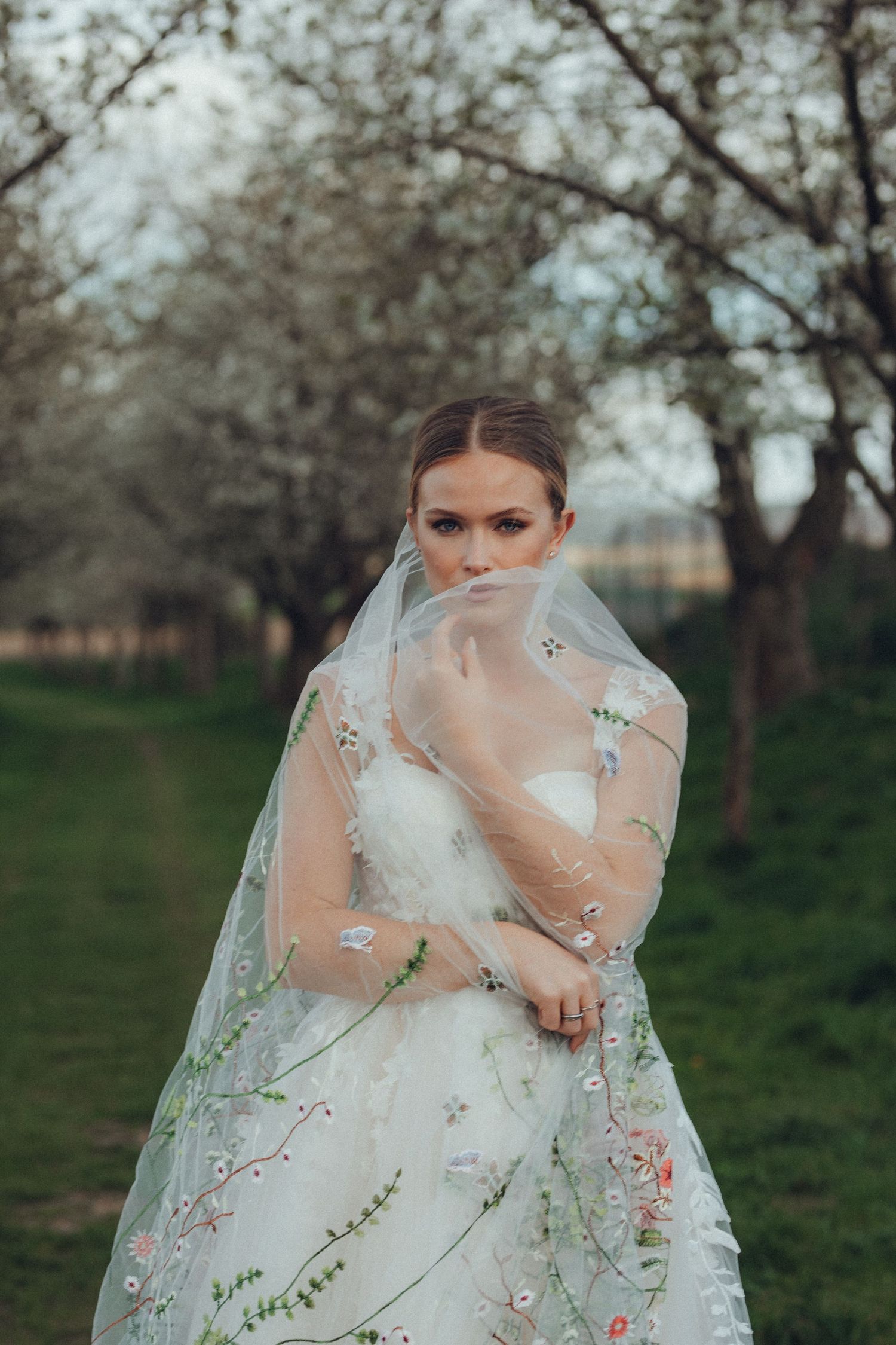 Dreamy bridal portrait showcasing intricate floral embellishments on a sheer veil in a garden setting.